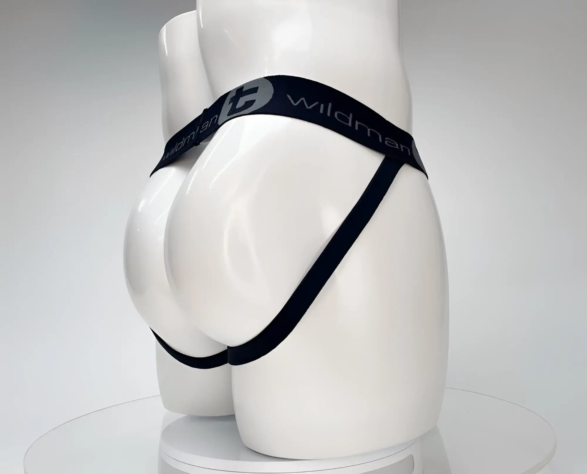 White WildmanT jockstrap on a mannequin, featuring a black branded elastic waistband and side straps.