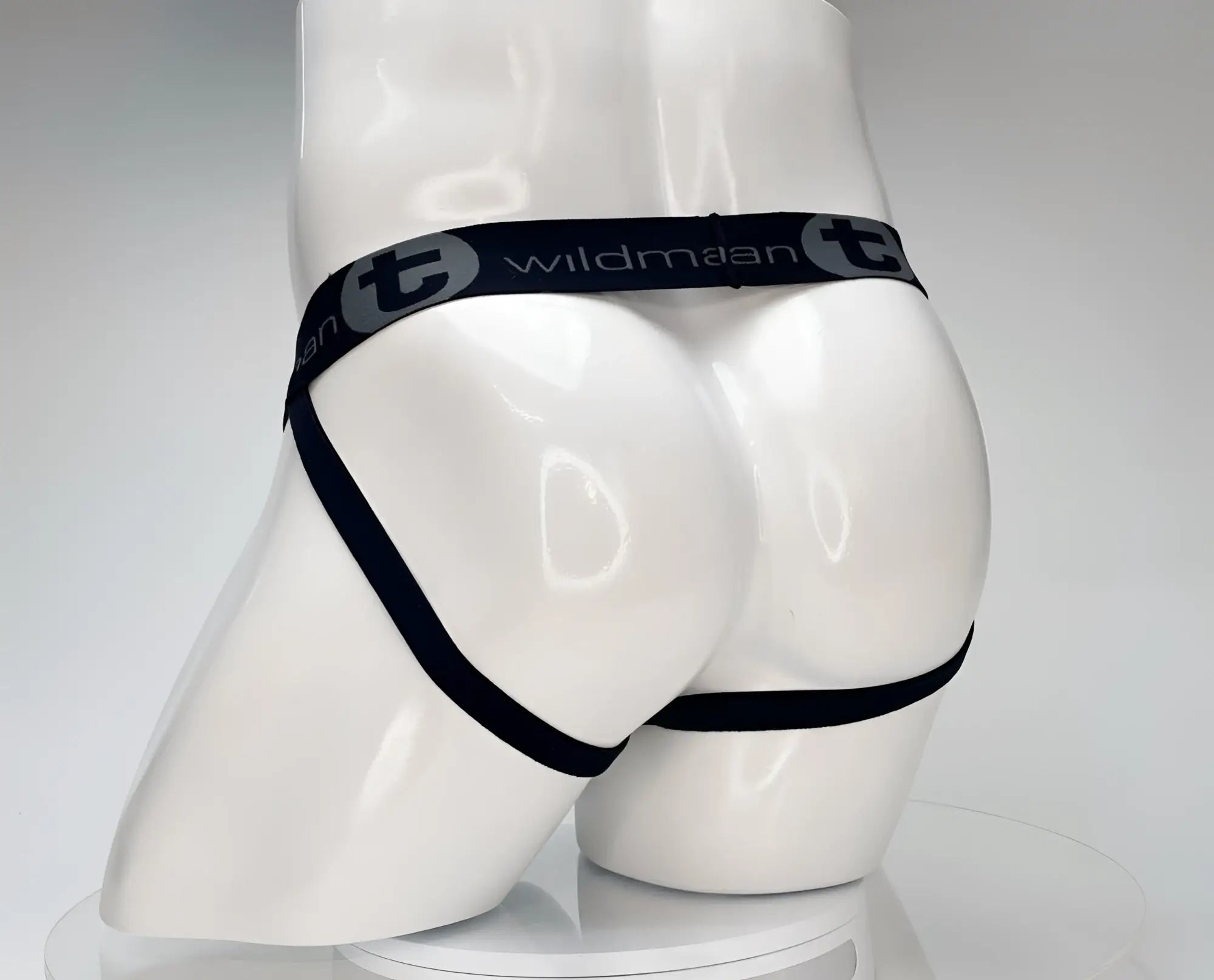 White WildmanT jockstrap on a mannequin, featuring a black branded elastic waistband and thin leg straps.