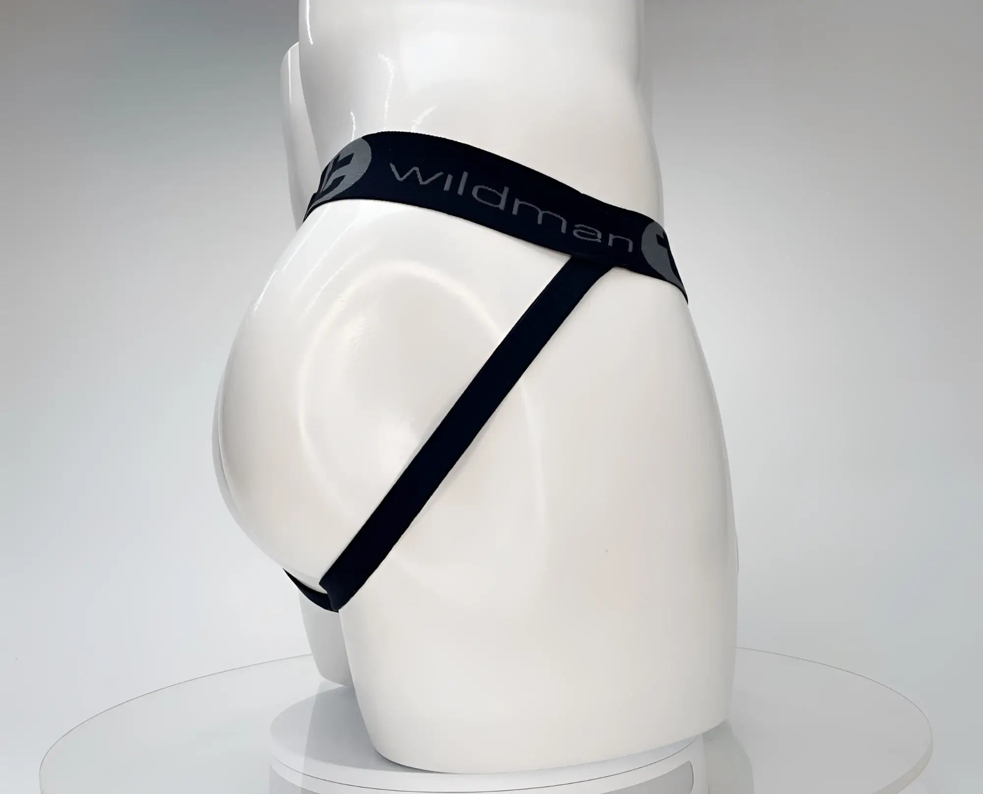 White mannequin wearing a black WildmanT jockstrap with branded elastic waistband on a white background.