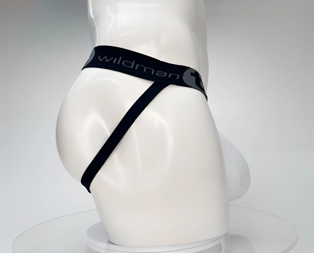 White WildmanT jockstrap on a mannequin, featuring a black waistband with gray logo text and a minimalist strap design.