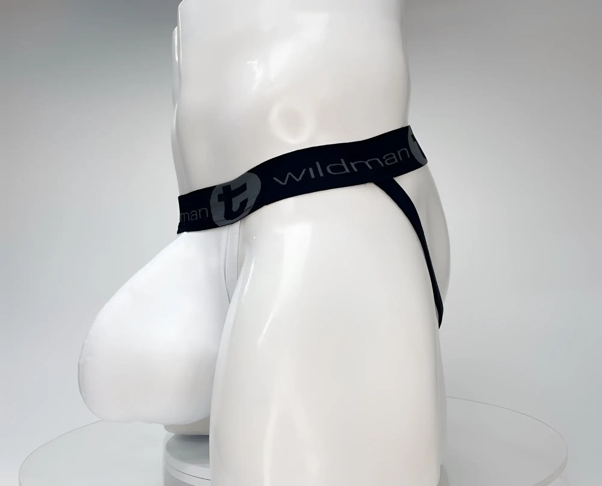 White WildmanT jockstrap with a large, contoured front pouch and a black branded elastic waistband on a mannequin.