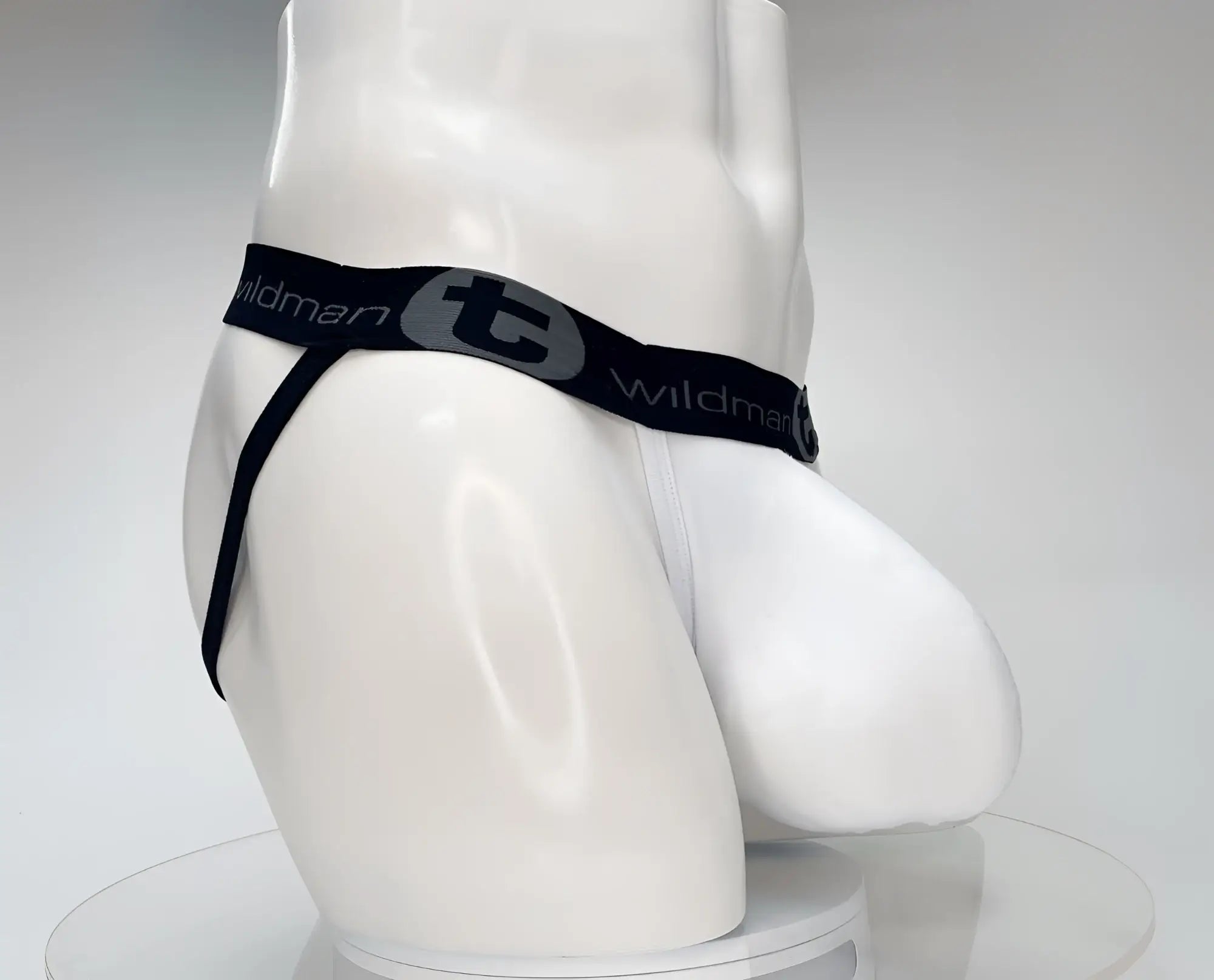 White cotton jockstrap with a prominent pouch, black branded elastic waistband with "Wildman" and logo, side view.