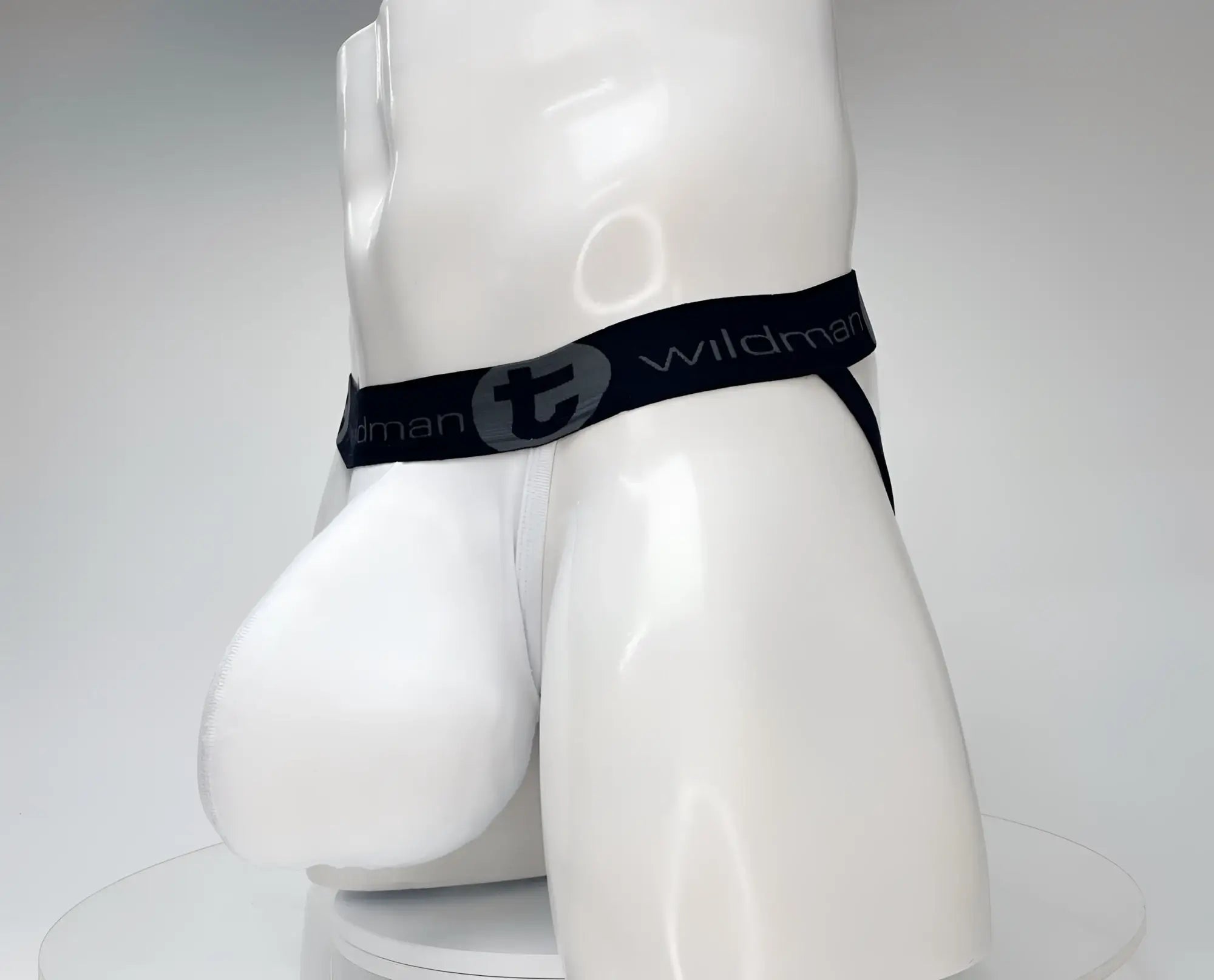 White jockstrap on a mannequin with a large contoured pouch and a black waistband featuring the WildmanT logo.