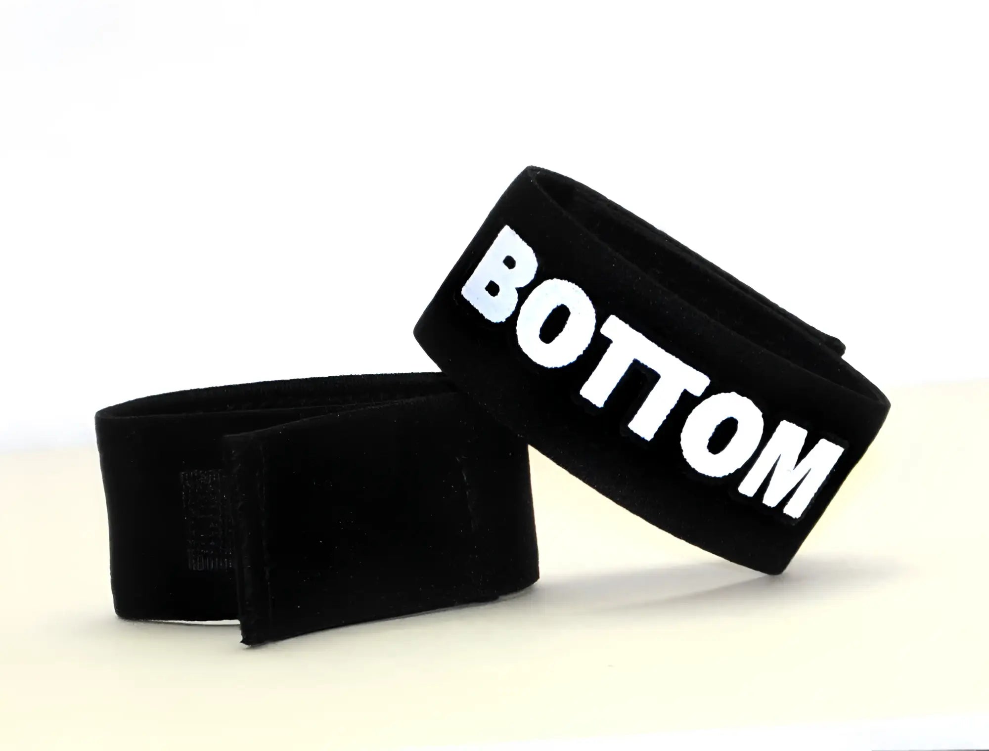 Black fabric cock ring with a Velcro closure, featuring the word "BOTTOM" in bold white lettering.