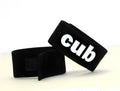 Two black adjustable fabric cock rings with "cub" embroidered in white lettering on one side and velcro closures.