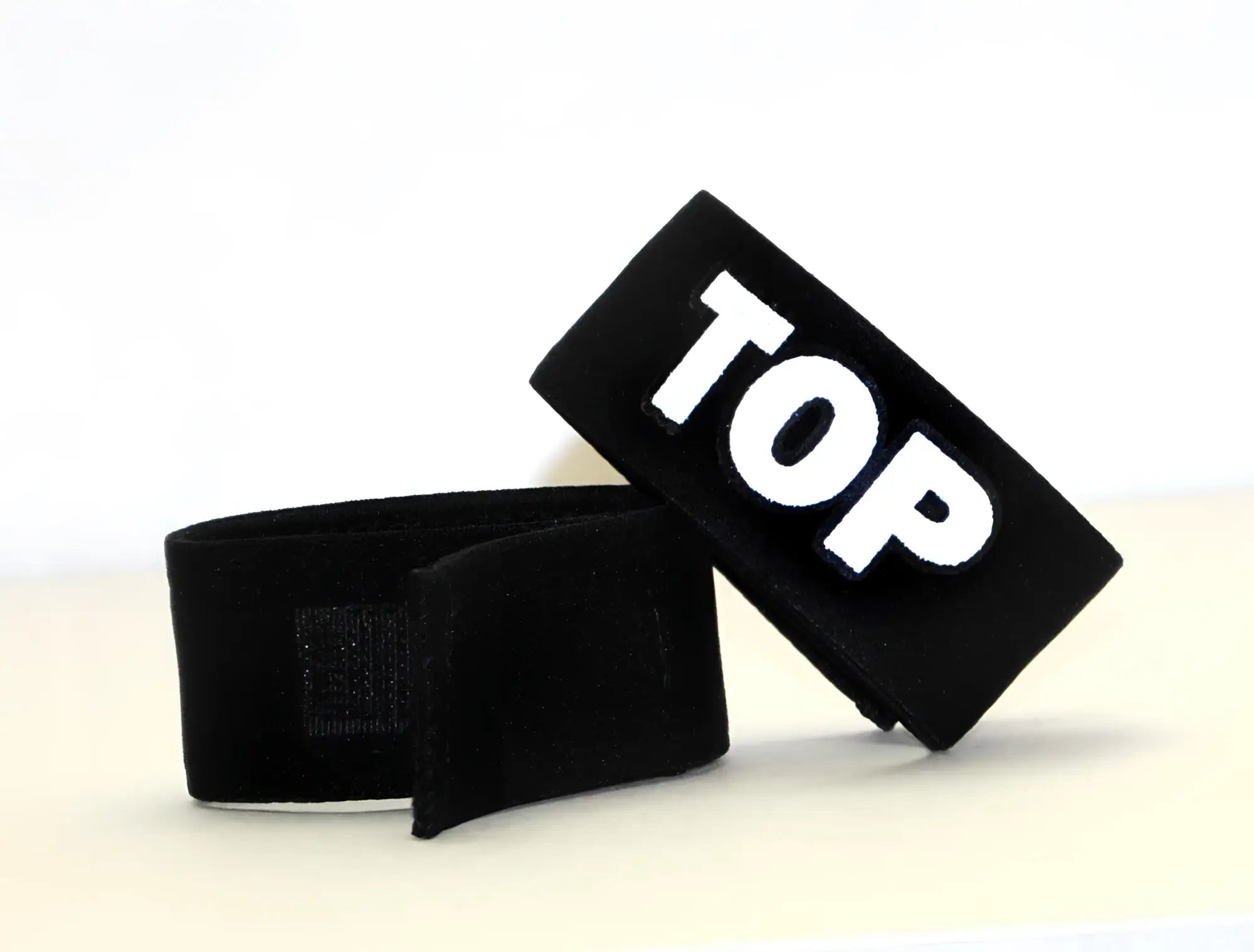Black fabric adjustable cock ring with "TOP" in bold white lettering, featuring a velcro closure.
