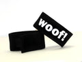 Black, adjustable fabric cock ring with white "WOOF!" lettering, featuring a velcro closure.