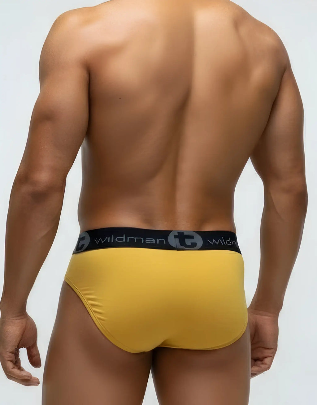 Muscular man wearing gold WildmanT modal pouch briefs with a black branded waistband, seen from behind.