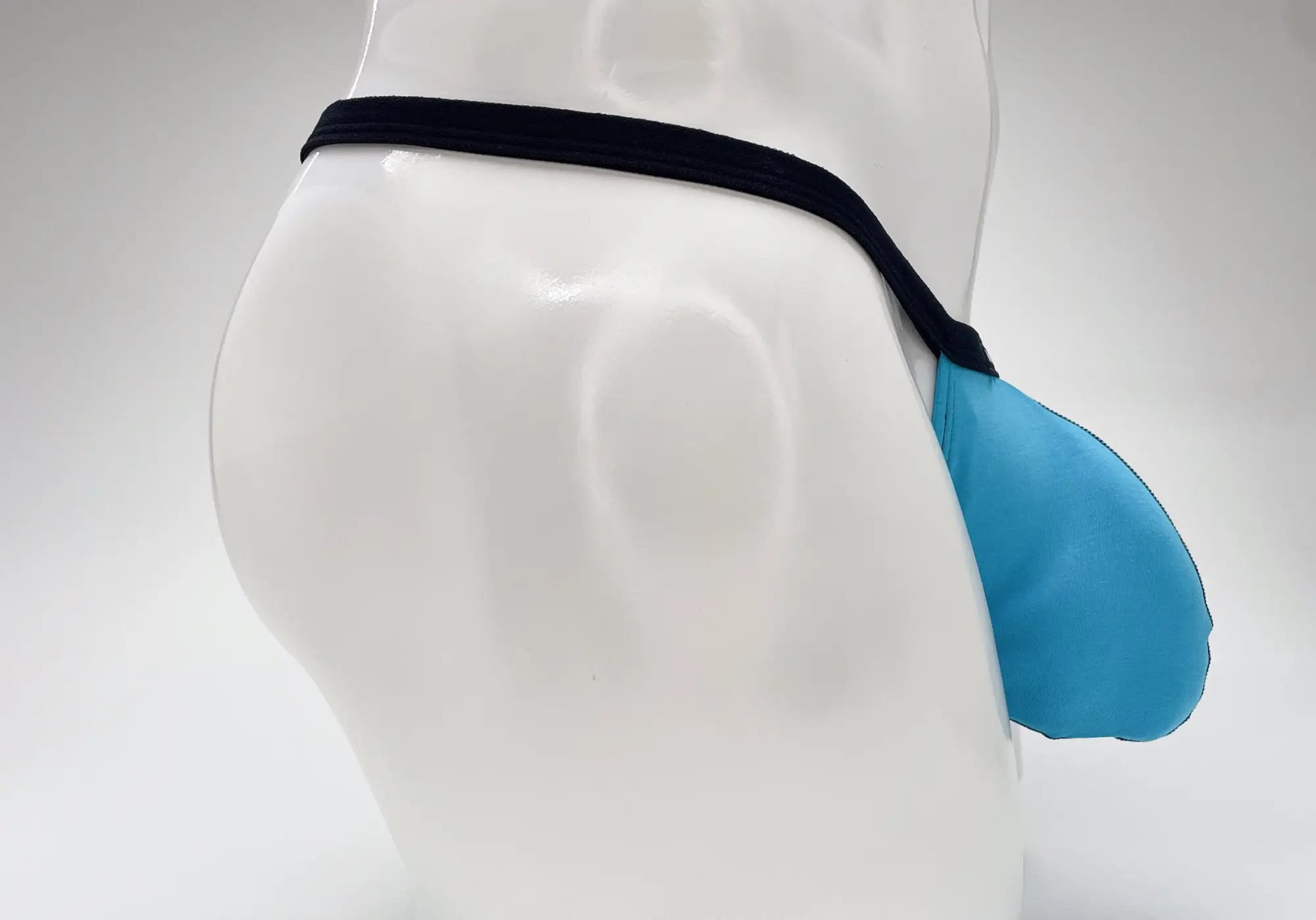 Baby blue micro thong with a prominent pouch and thin black waistband, displayed on a white mannequin.