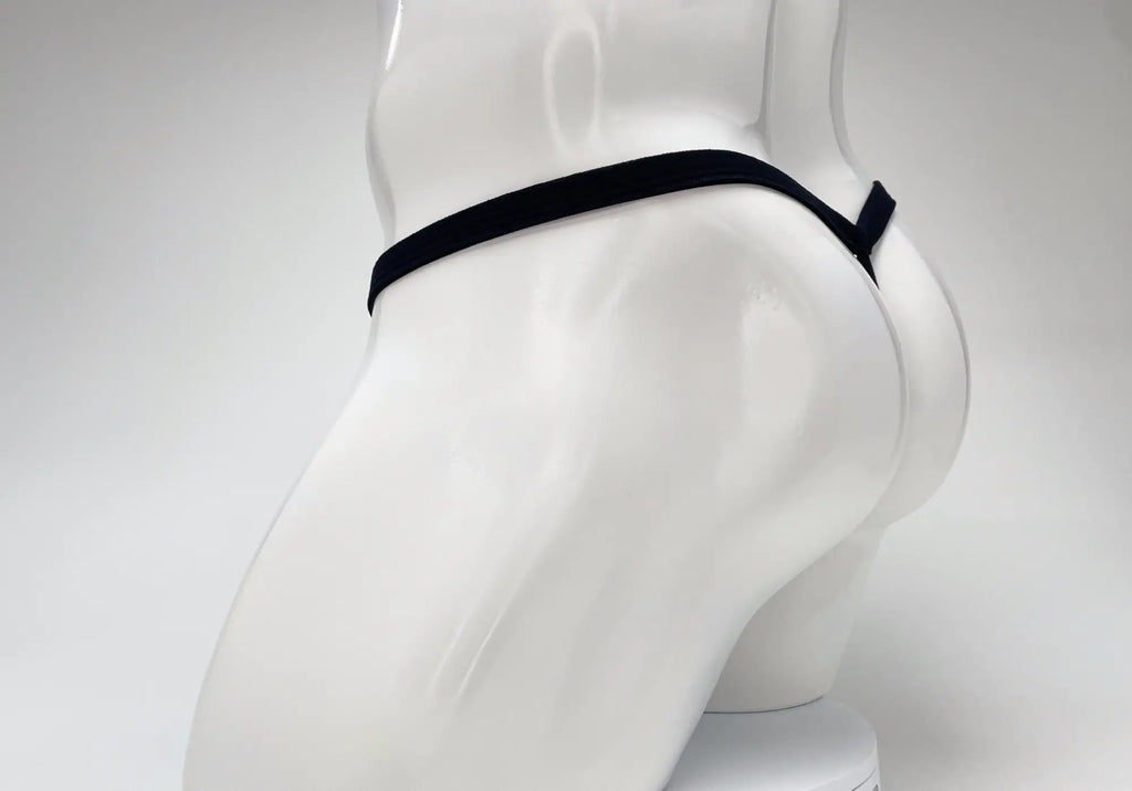 A side view of a white male mannequin torso wearing a minimalist black thong with a thin waistband on a white background.