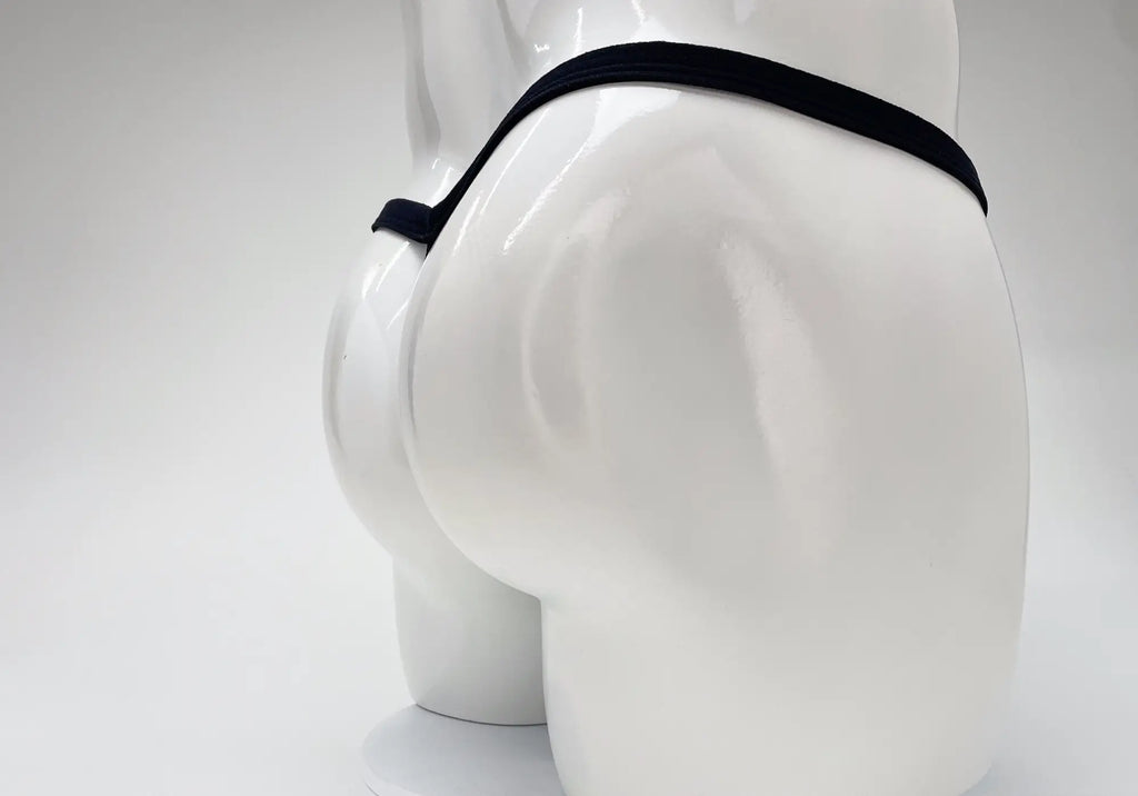 A back view of a white mannequin wearing a thin, black micro thong with a minimalist strap design.