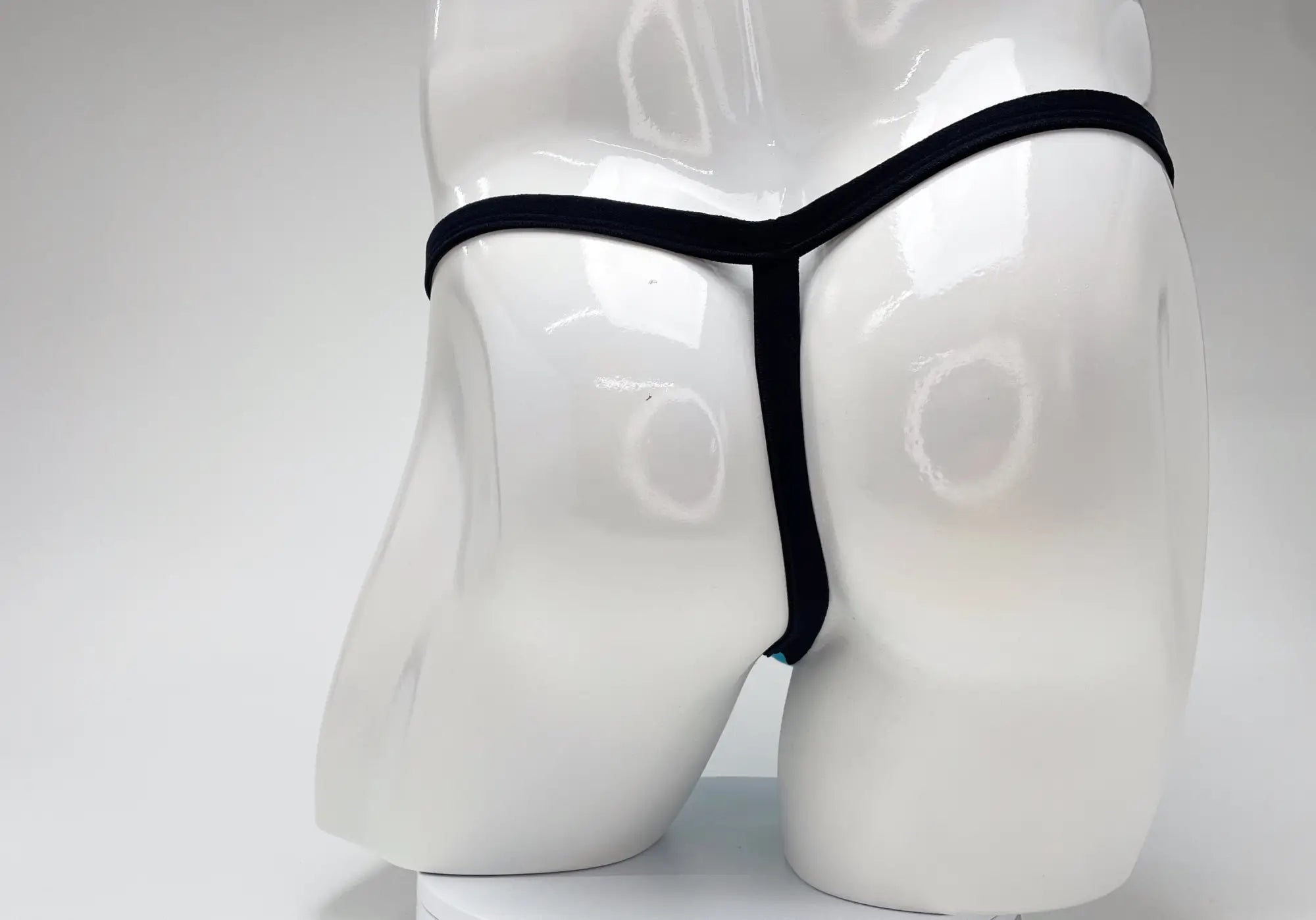 Back view of a baby blue modal micro thong with thin black elastic trim on a white mannequin.