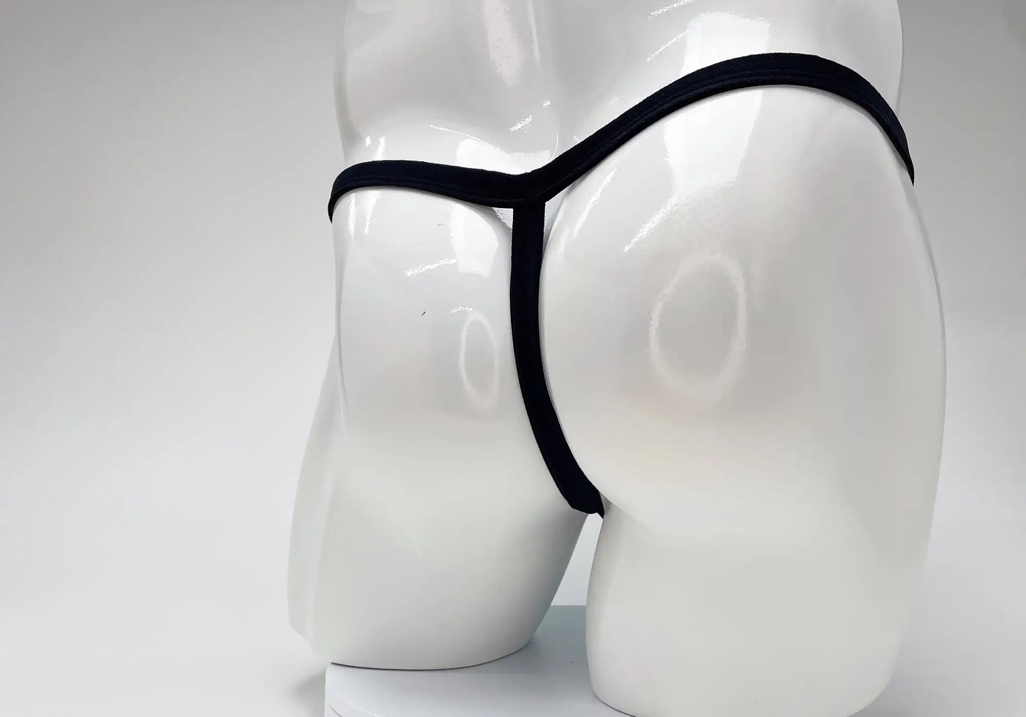 Black WildmanT micro thong with thin waistband and minimalist back design, shown on a white mannequin.
