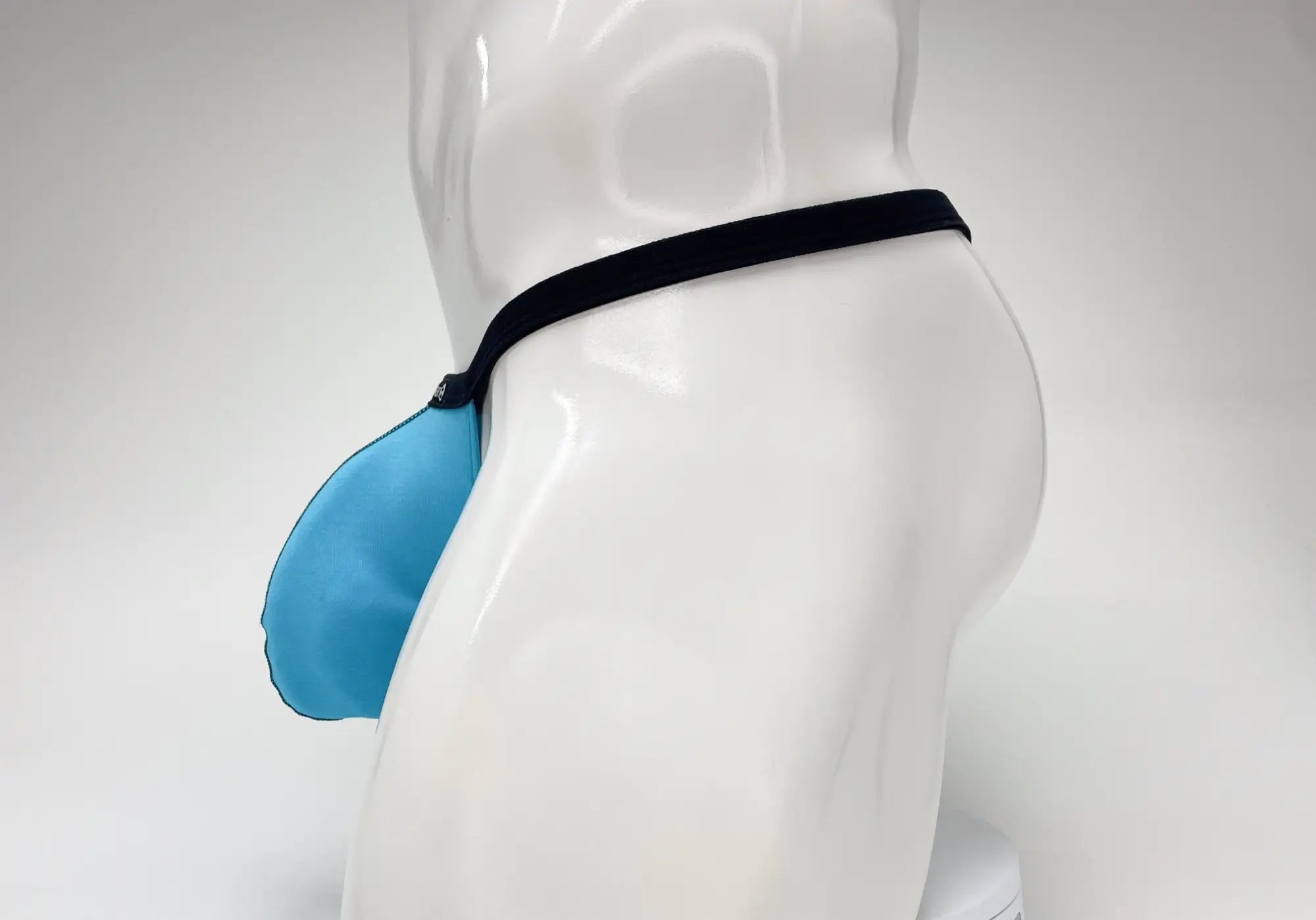 Baby blue WildmanT modal micro thong with a large pouch and thin black waistband on a white mannequin torso.
