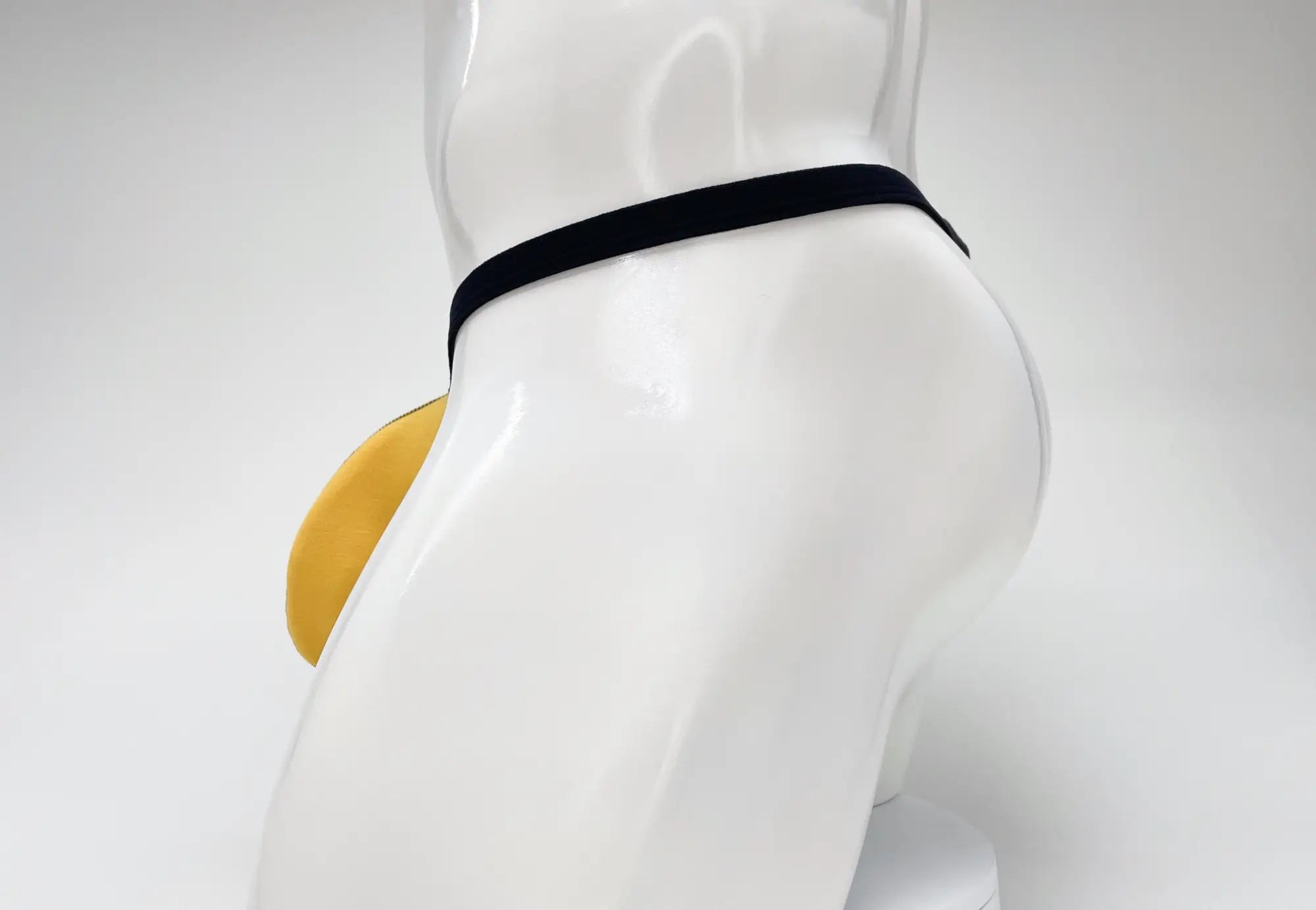 WildmanT gold modal micro thong with a large pouch, shown on a white mannequin torso from a side profile view.