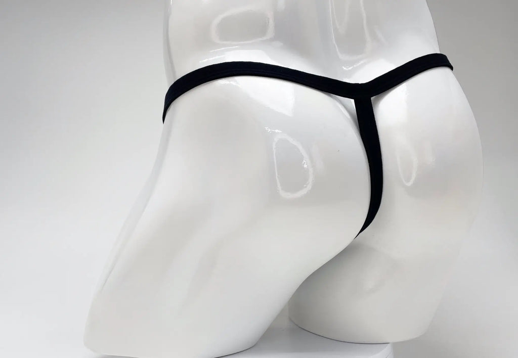 WildmanT modal micro thong in black, worn on a glossy white male mannequin, shown from the back view.