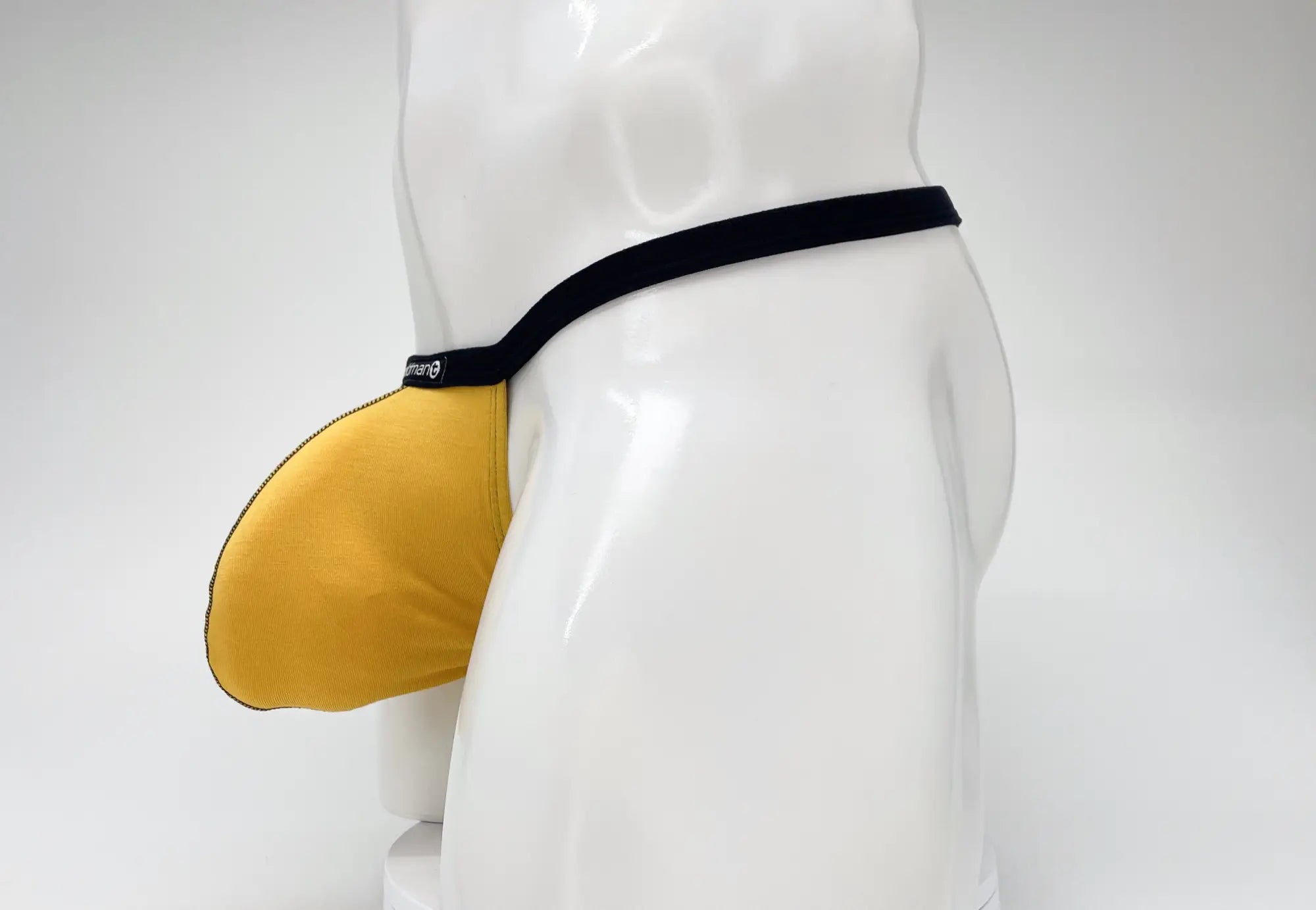 WildmanT gold modal micro thong with a prominent big boy pouch, featuring black trim and branding on a white mannequin.