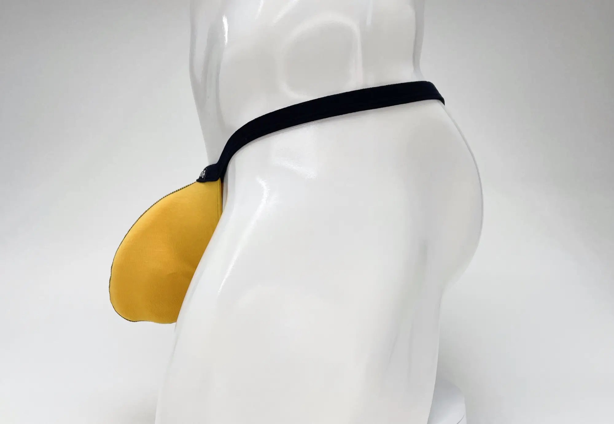 WildmanT Modal Micro thong in gold with a prominent pouch, featuring a slim black waistband on a white mannequin.
