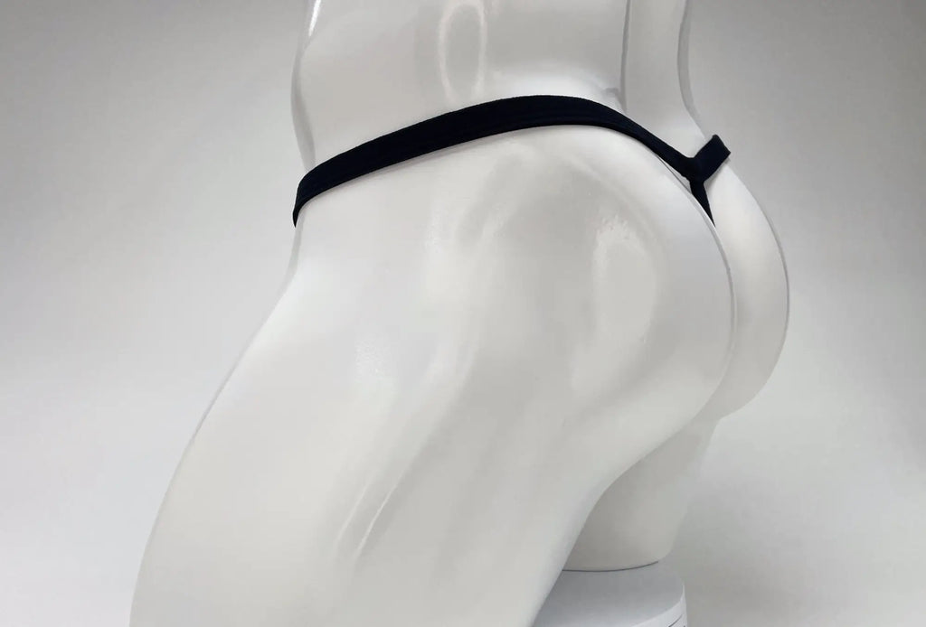 Black micro thong on a white mannequin, showing a minimalist string design from a side-rear perspective.