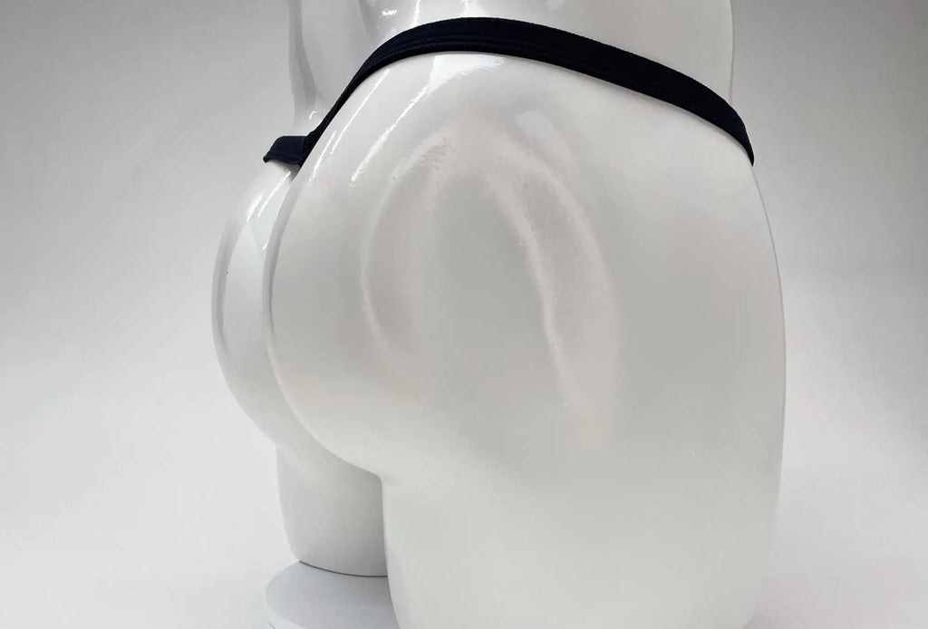 A white male mannequin torso wearing a minimalist black thong with a thin waistband against a white background.