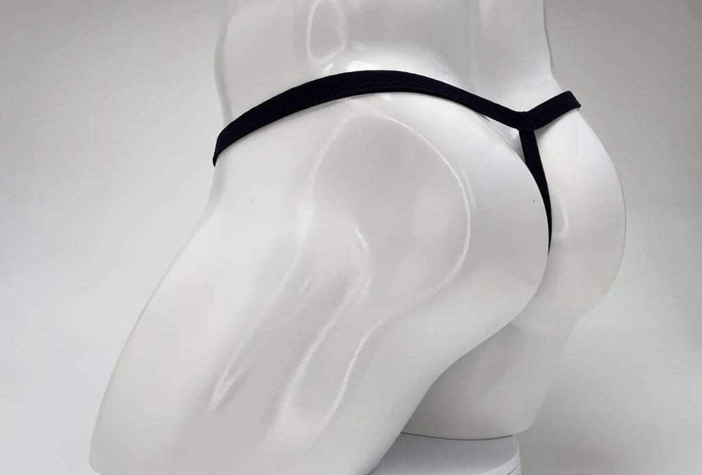 A black WildmanT micro thong with thin straps shown from behind on a white mannequin torso.