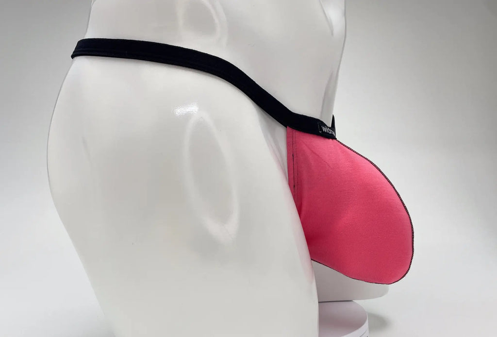 WildmanT pink modal micro thong with a prominent big boy pouch and black elastic waistband on a white mannequin torso.