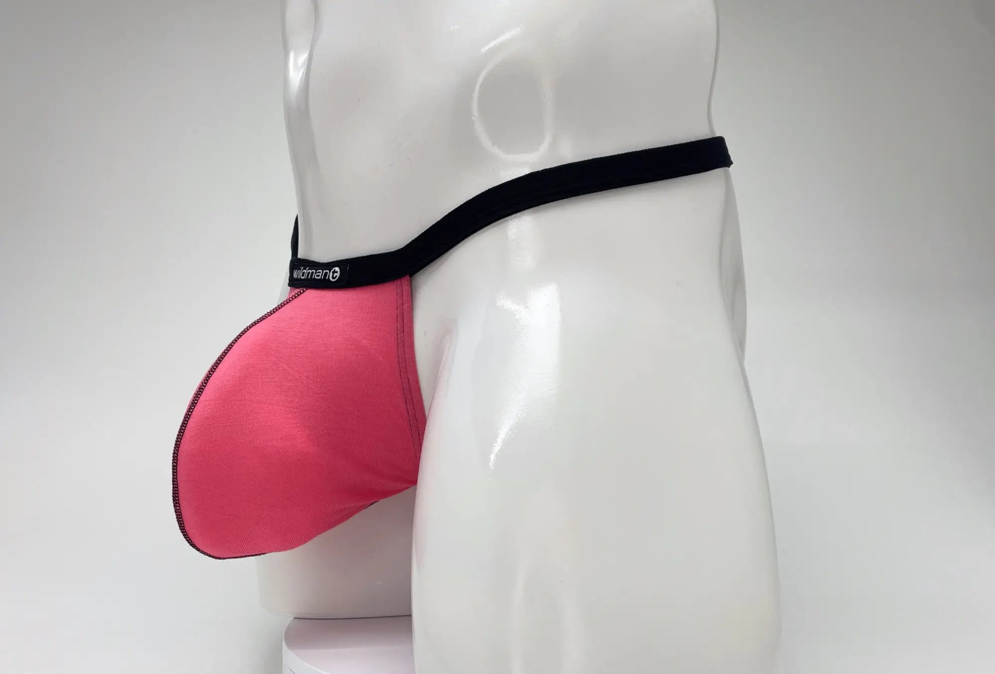WildmanT pink modal micro thong with a prominent big boy pouch, featuring a black waistband and trim on a mannequin.