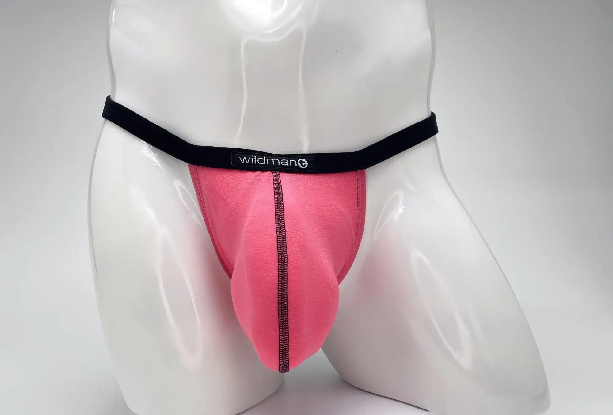 Bright pink modal micro thong with a prominent pouch, black trim, and a WildmanT logo on a white mannequin.