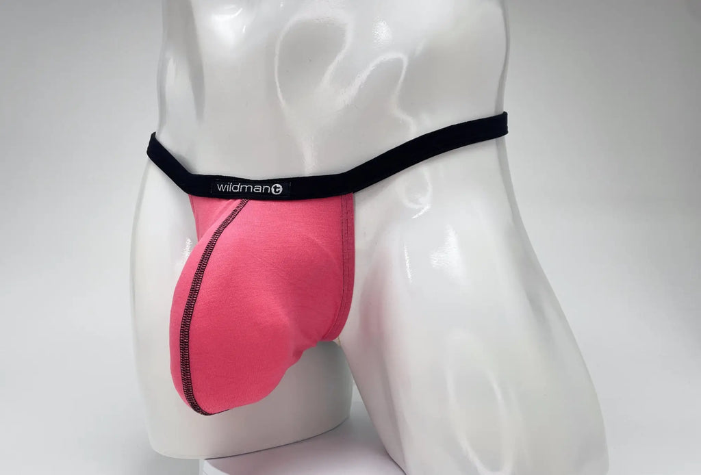 Pink modal micro thong with a large pouch, black waistband, and WildmanT logo, modeled on a white mannequin.