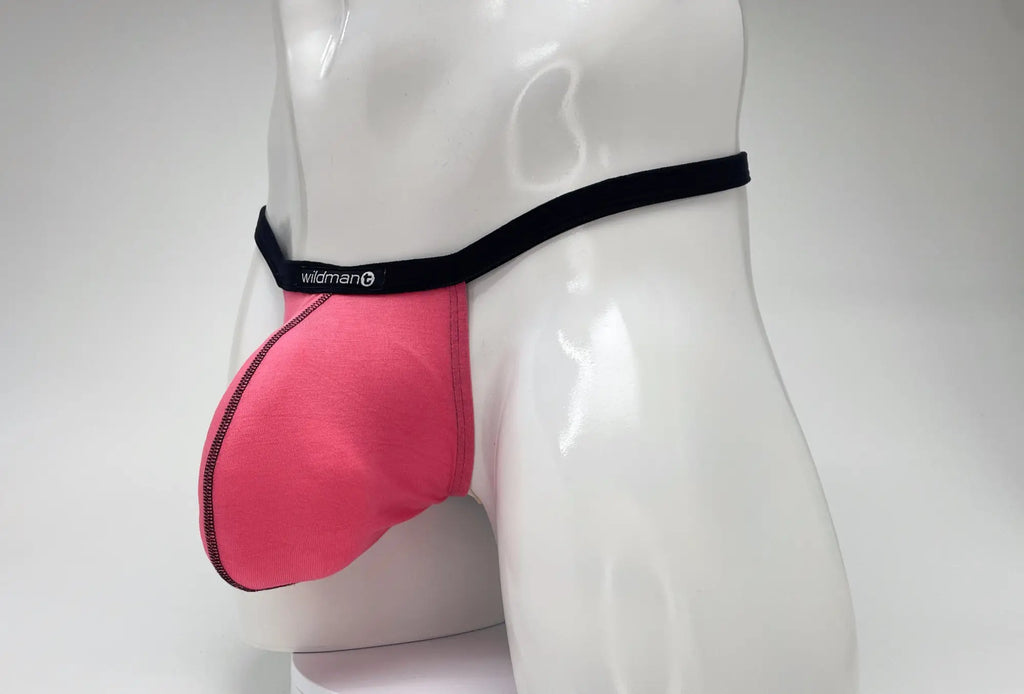 WildmanT pink modal micro thong with a prominent big boy pouch and black branded waistband on a mannequin torso.