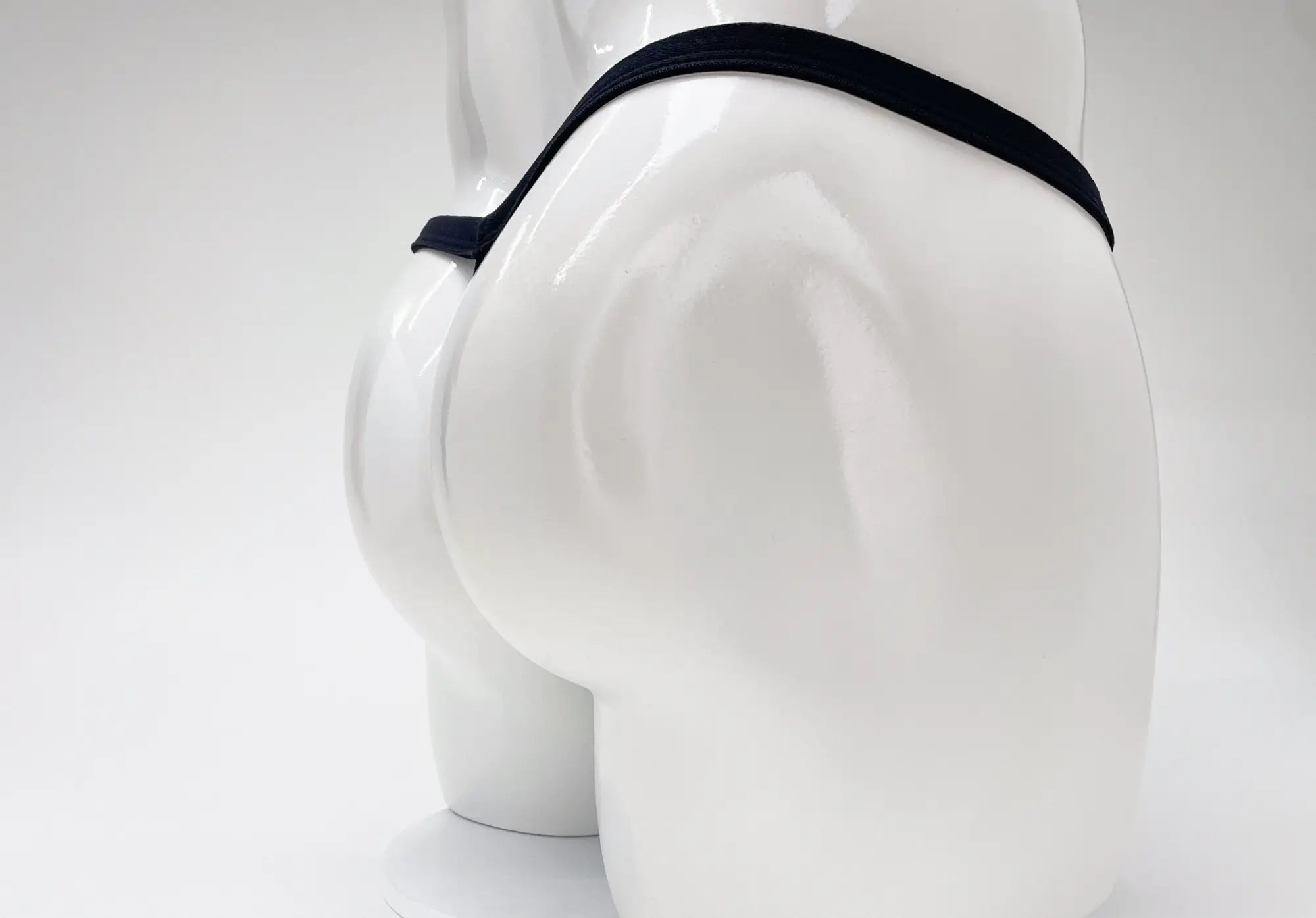 Rear view of a white mannequin wearing a purple modal thong with a minimalist waistband.