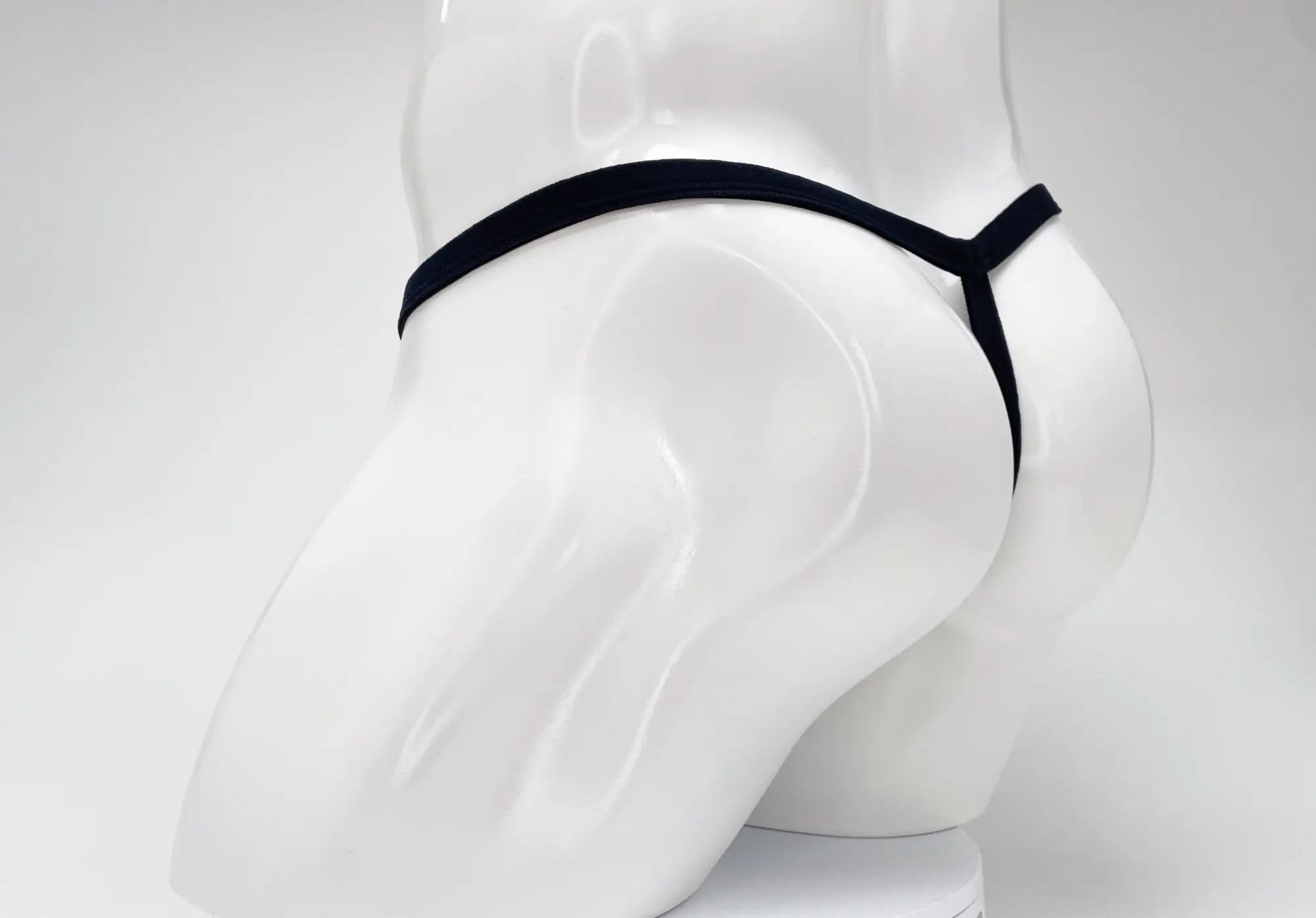 Purple WildmanT micro thong with a thin waistband and minimalist rear coverage on a white mannequin.