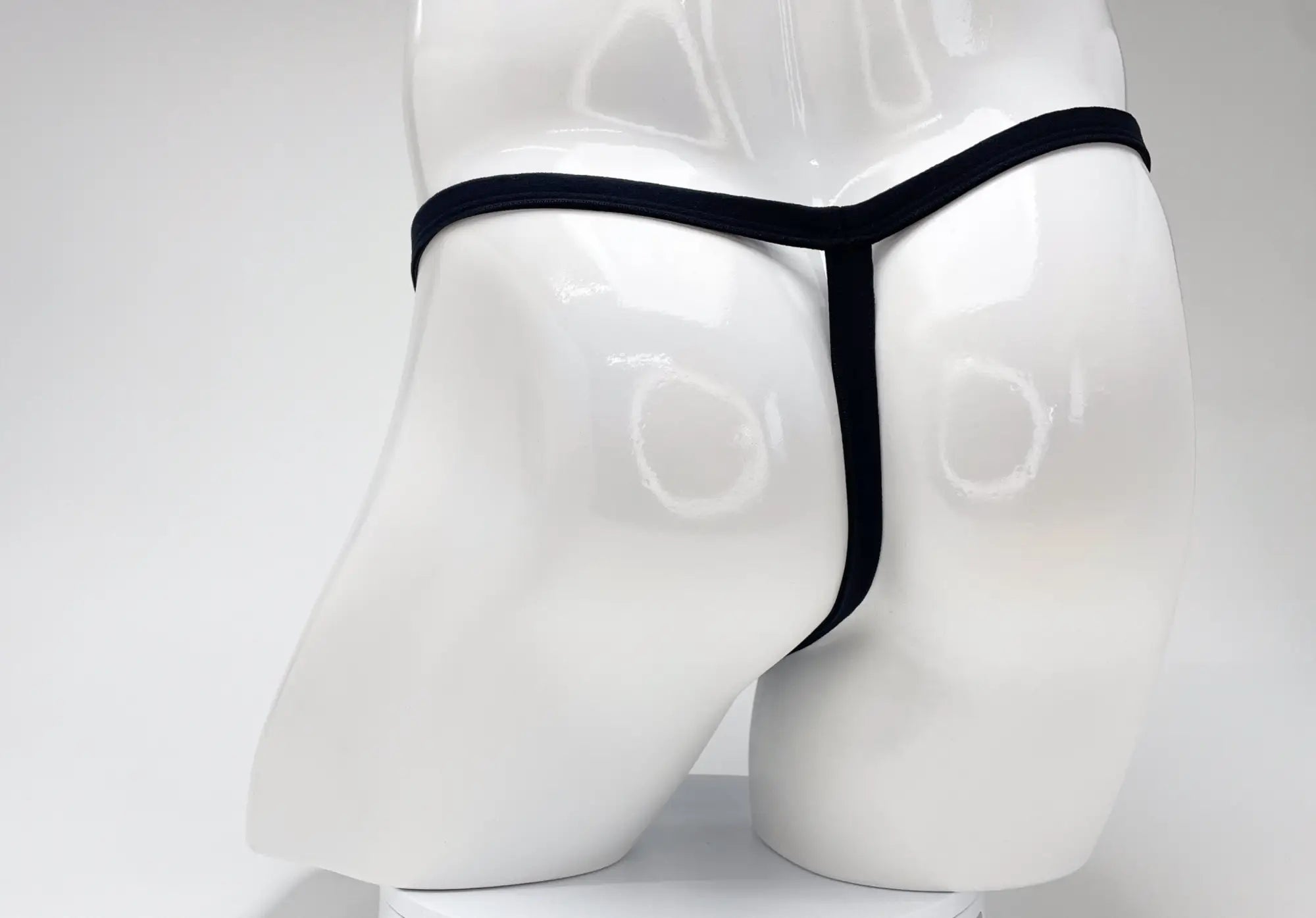 Back view of a purple WildmanT modal micro thong with a thin waistband on a glossy white mannequin torso.
