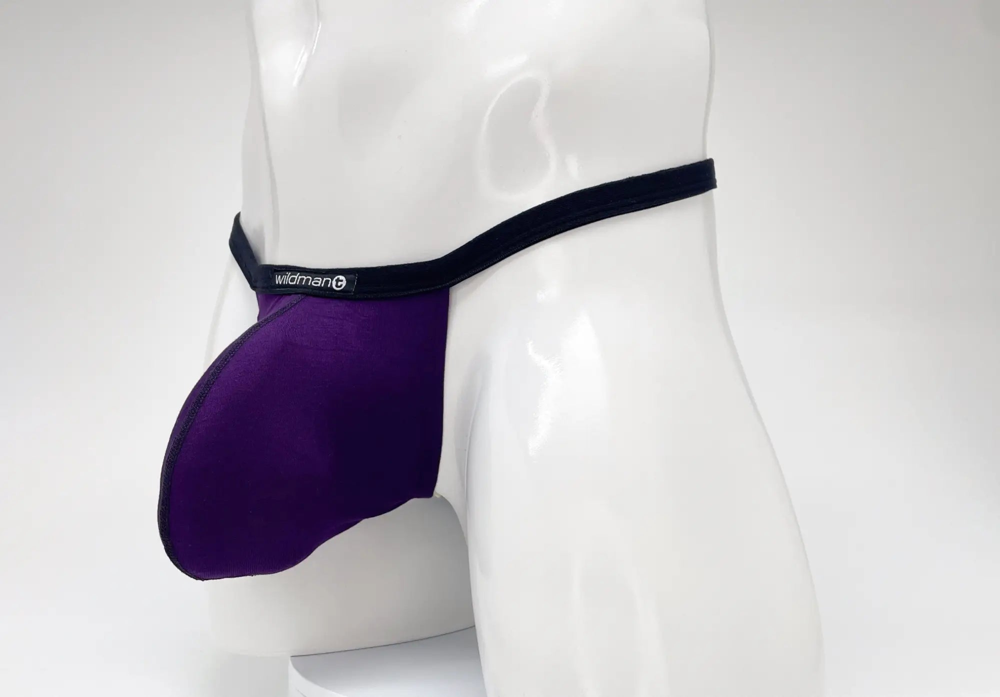 Purple WildmanT modal micro thong with a prominent pouch, black trim, and a branded logo tag on a white mannequin.