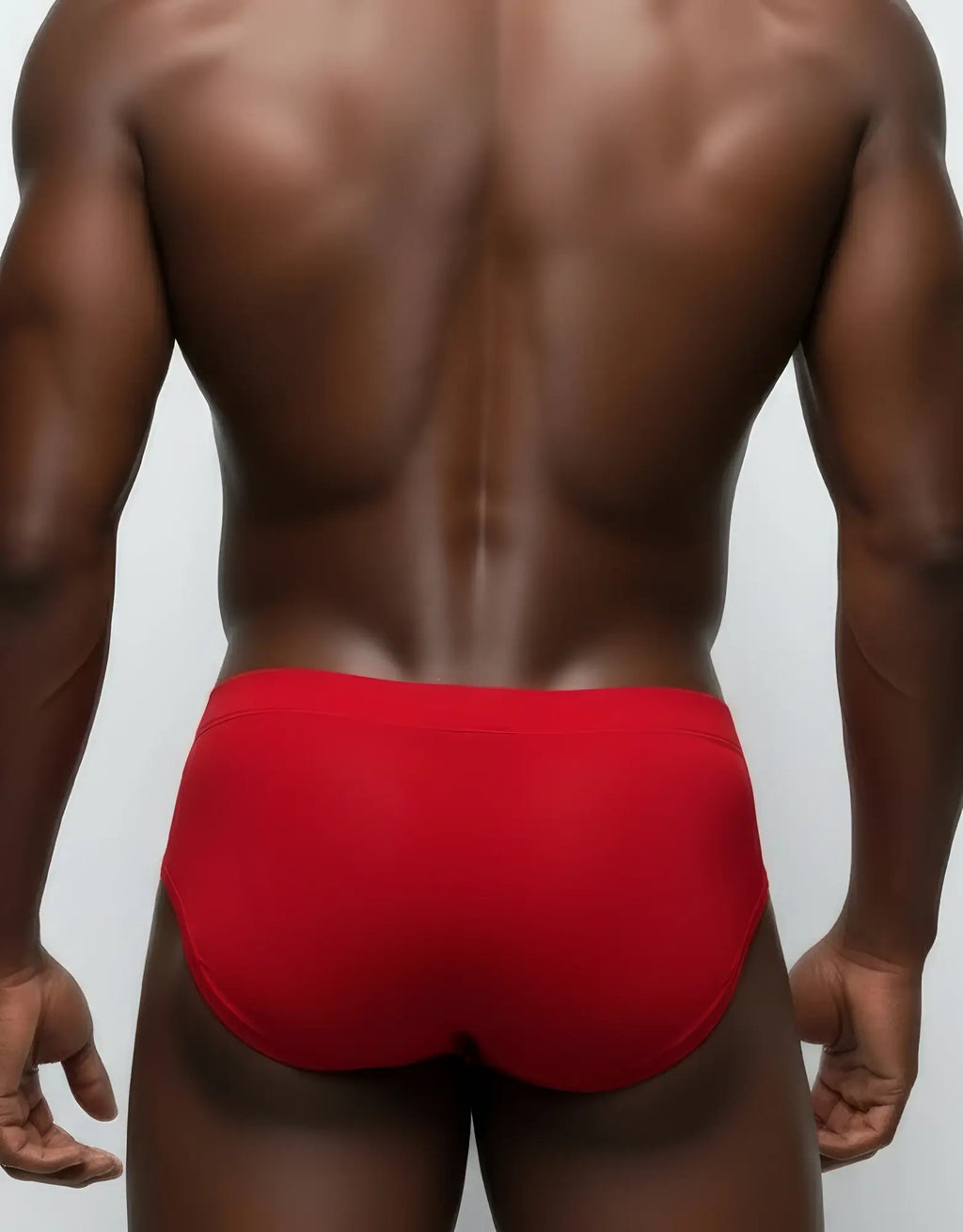 Back view of a man wearing red mesh briefs with a solid waistband.