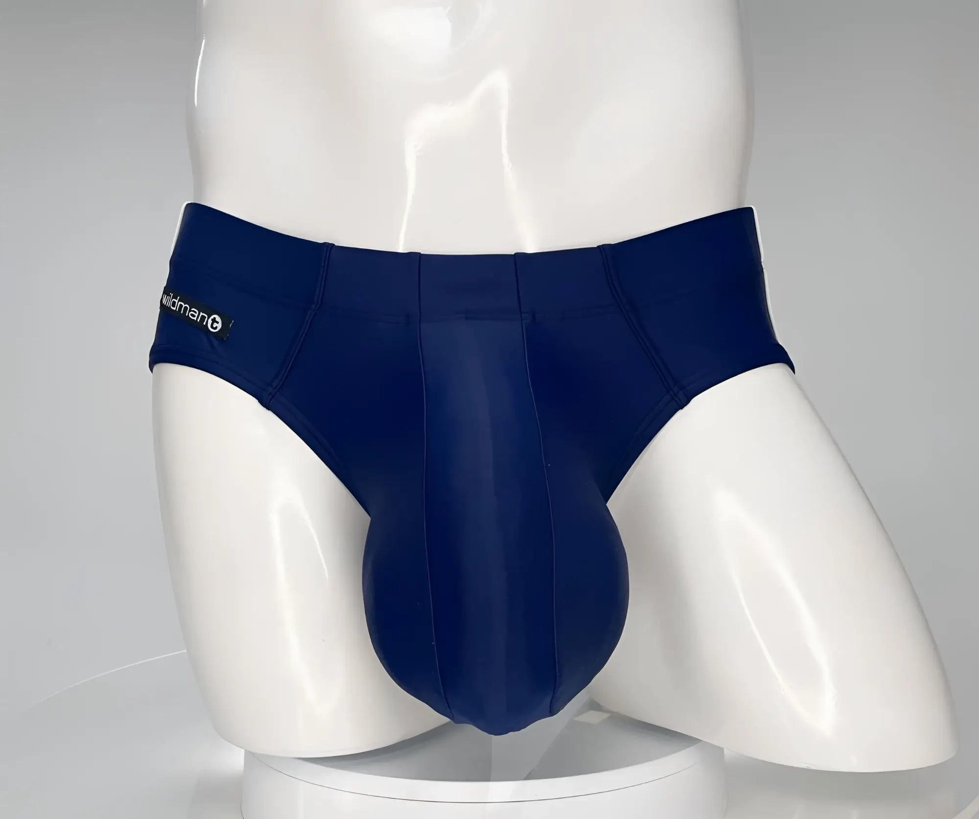 Navy blue WildmanT swim brief on a white mannequin with a prominent, contoured front pouch and side logo tag.