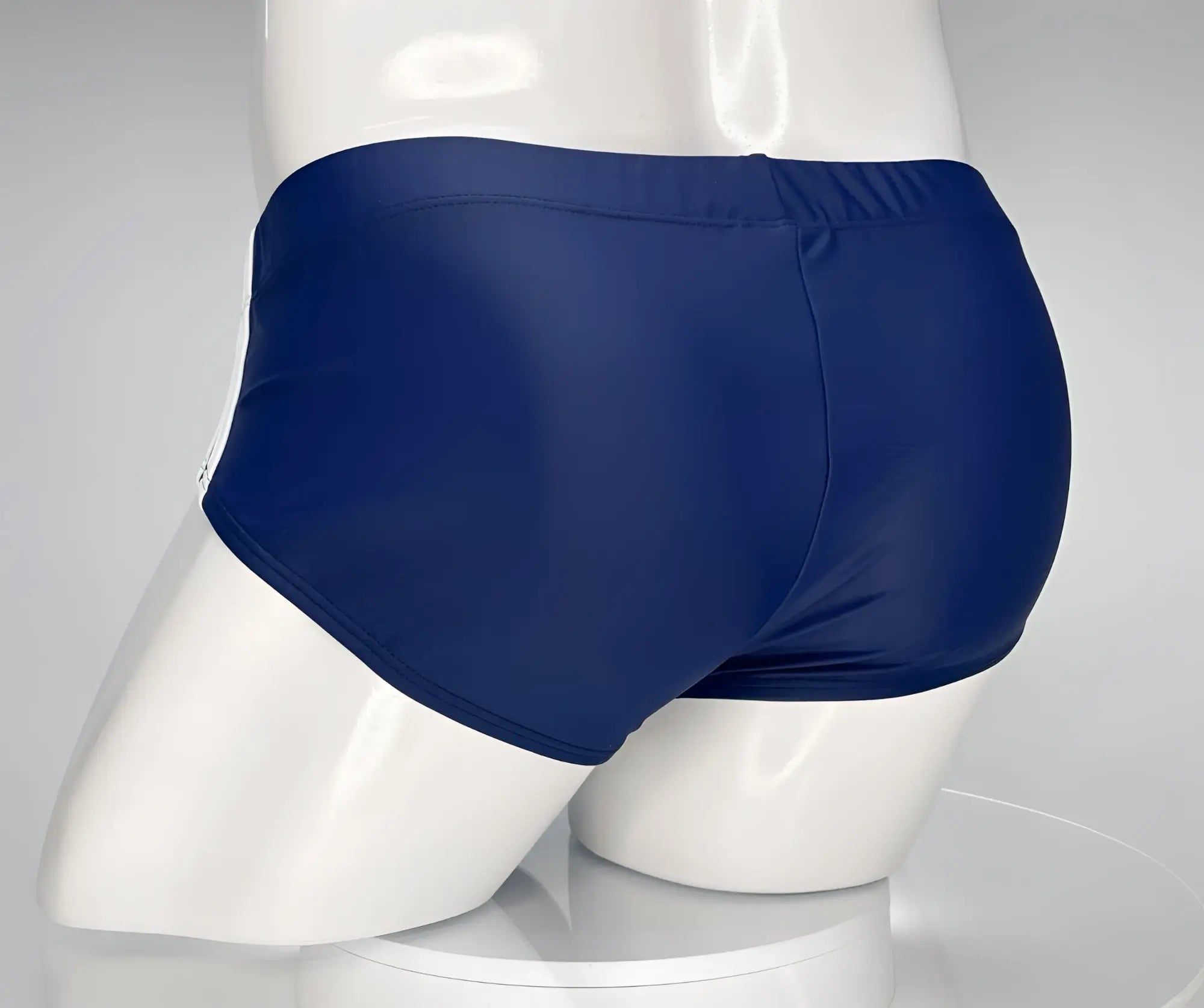 Back view of a navy blue WildmanT swim brief on a white mannequin, showing a solid color and athletic cut.