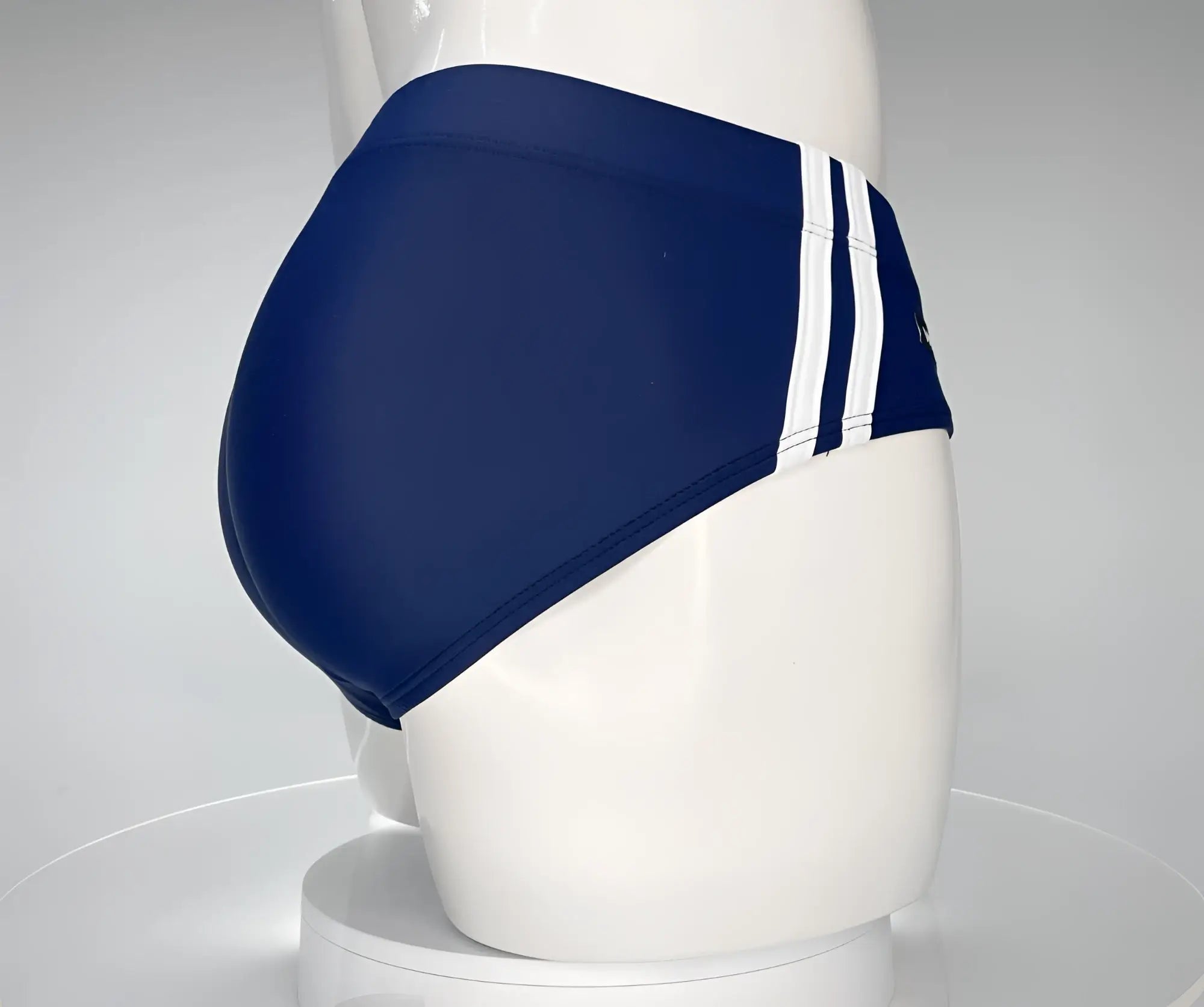 Navy blue WildmanT swim brief with white side stripes, displayed on a mannequin.