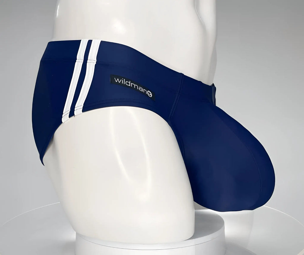 Navy blue WildmanT swim brief with white side stripes and a prominent contoured pouch on a white mannequin torso.