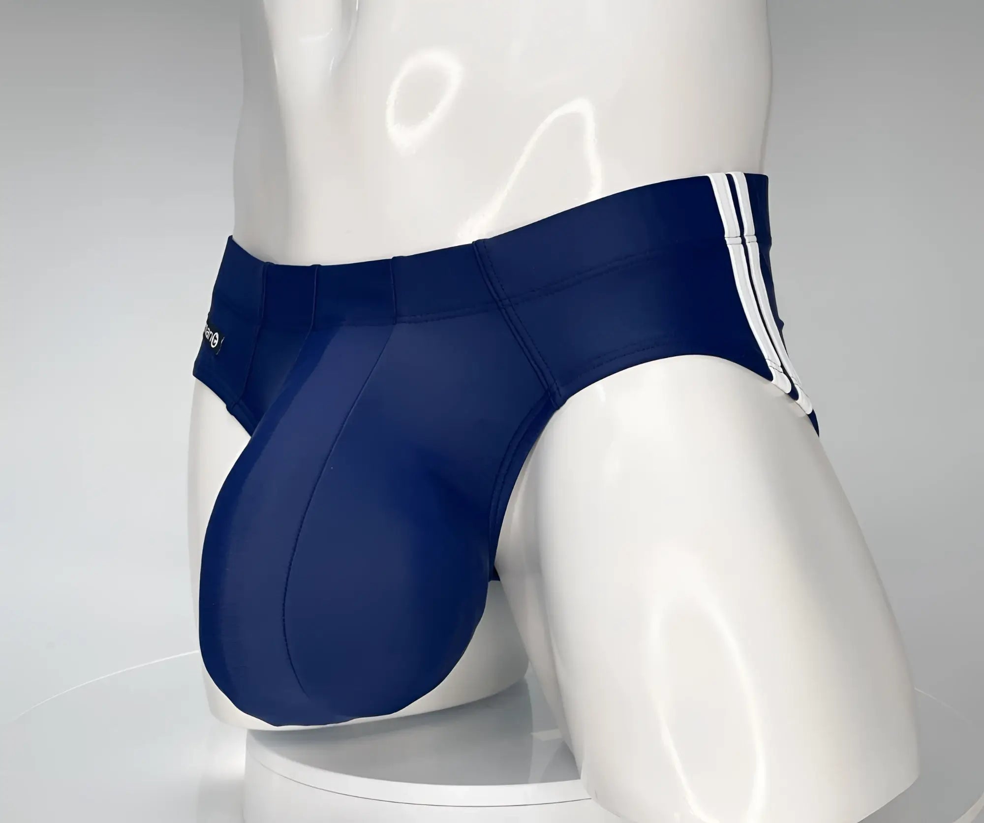 Navy blue swim brief with a large, contoured pouch and white side-stripe detailing on a mannequin torso.