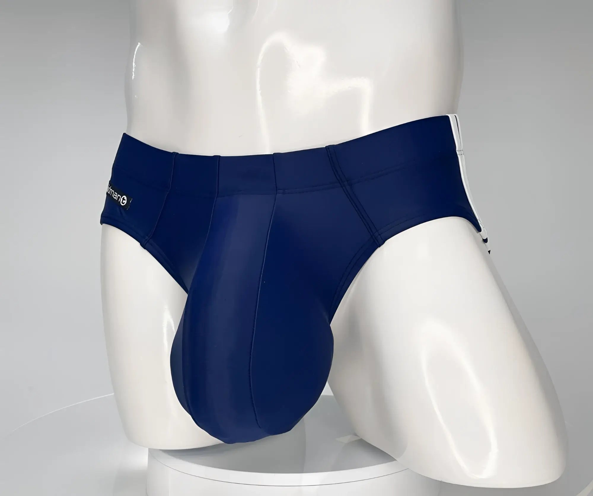 Navy blue WildmanT swim brief on a white mannequin, featuring a contoured pouch and white side stripe detailing.