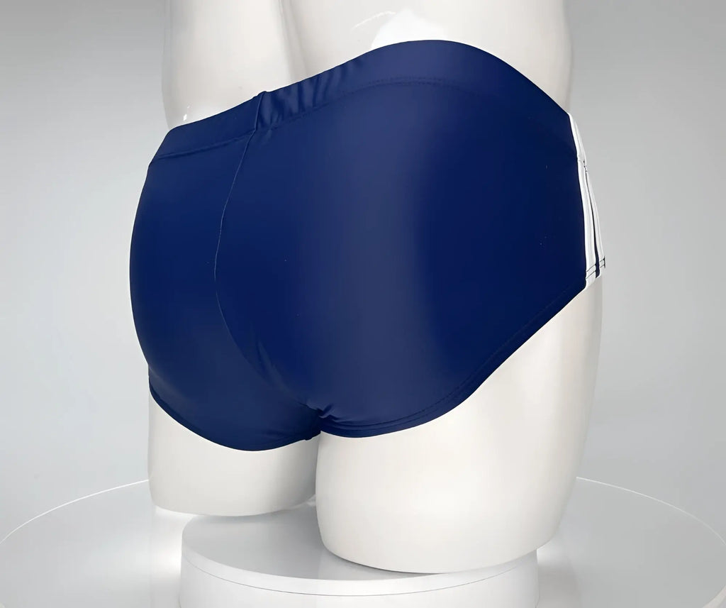 Navy blue WildmanT swim brief worn by a mannequin, featuring white side stripe detailing on a solid colored background.
