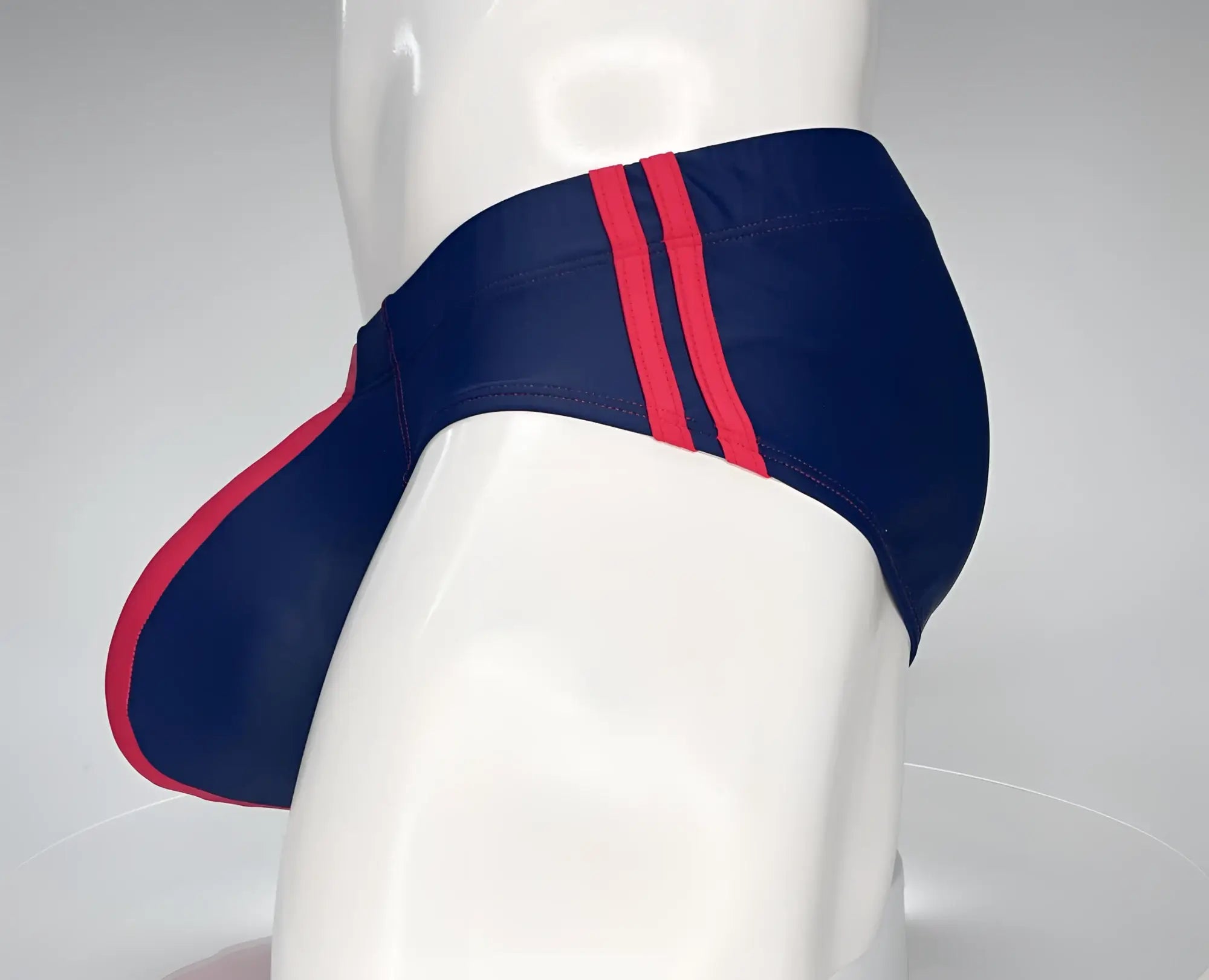 Navy blue swim brief with red trim and dual side stripes on a white mannequin.