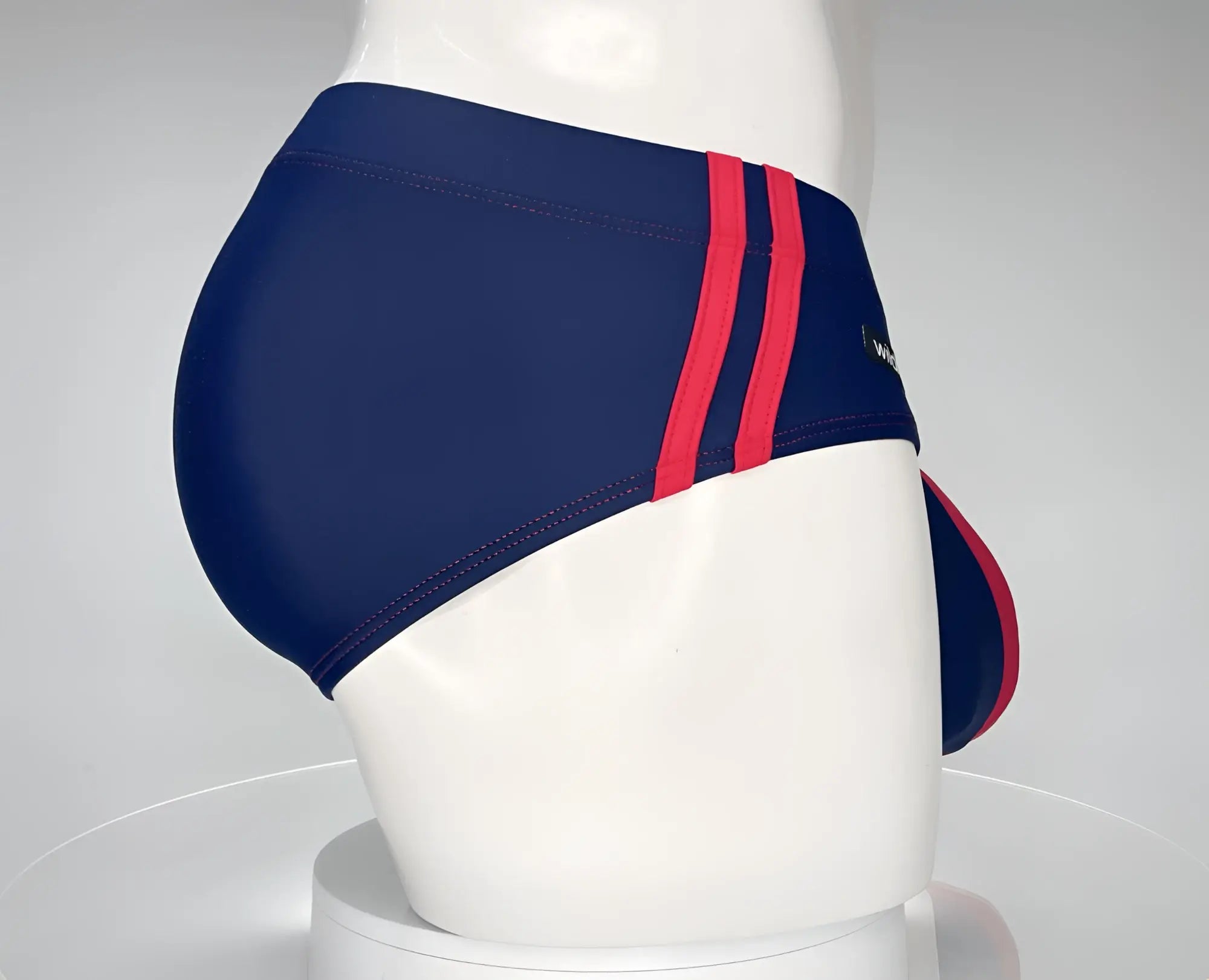 Navy blue swim brief with two red side stripes and a red front pouch trim, worn by a white mannequin.