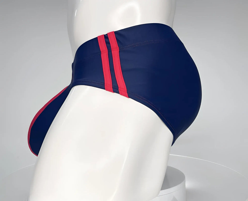 Navy blue WildmanT swim brief with two red side stripes and a red-trimmed front pouch on a mannequin torso.