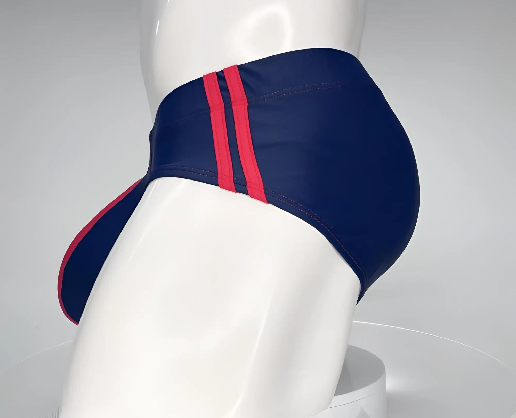 Navy blue WildmanT swim brief with two red side stripes and a red-trimmed front pouch on a mannequin torso.