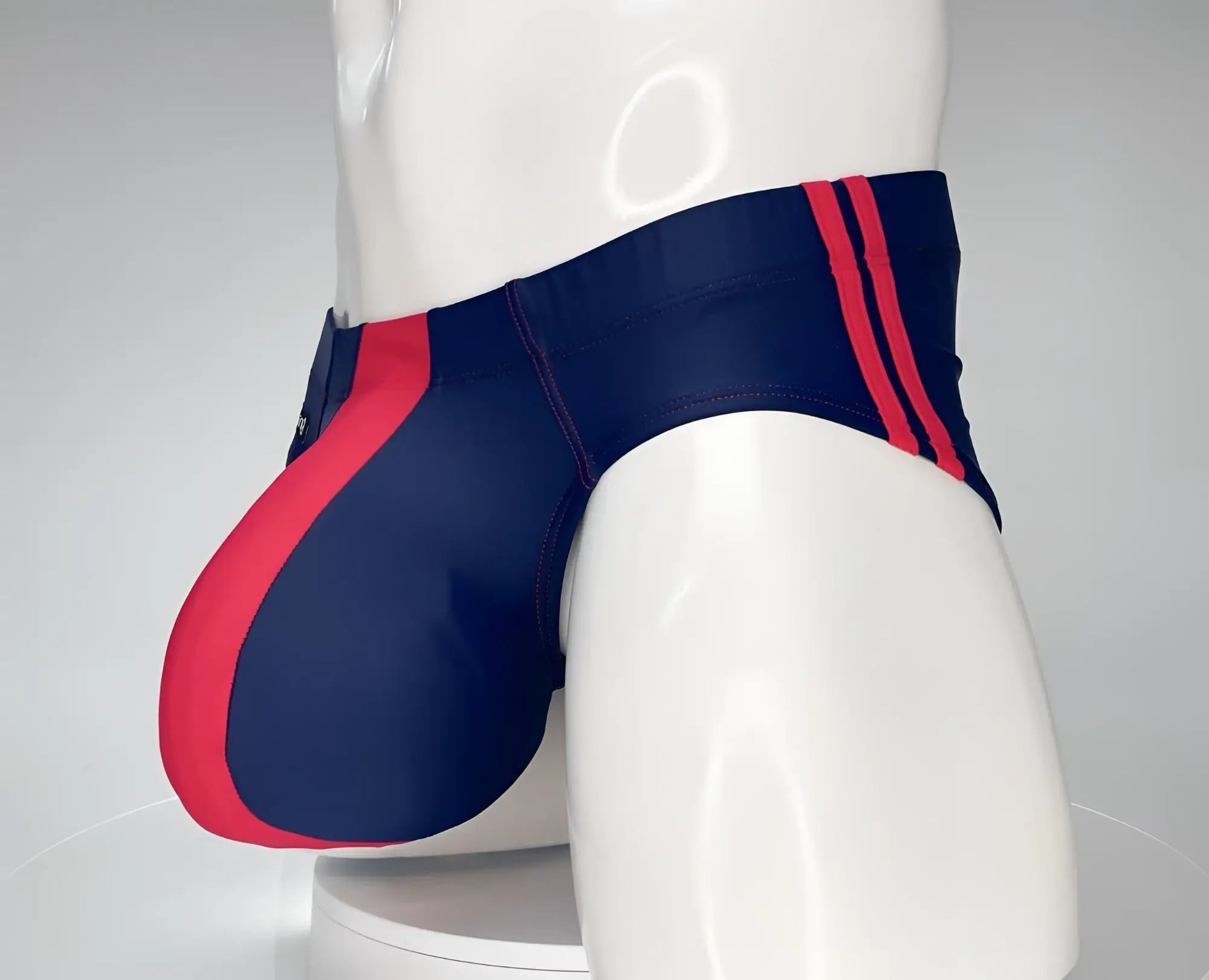 WildmanT navy and red swim brief with a contoured pouch, featuring side red stripes on a white mannequin.