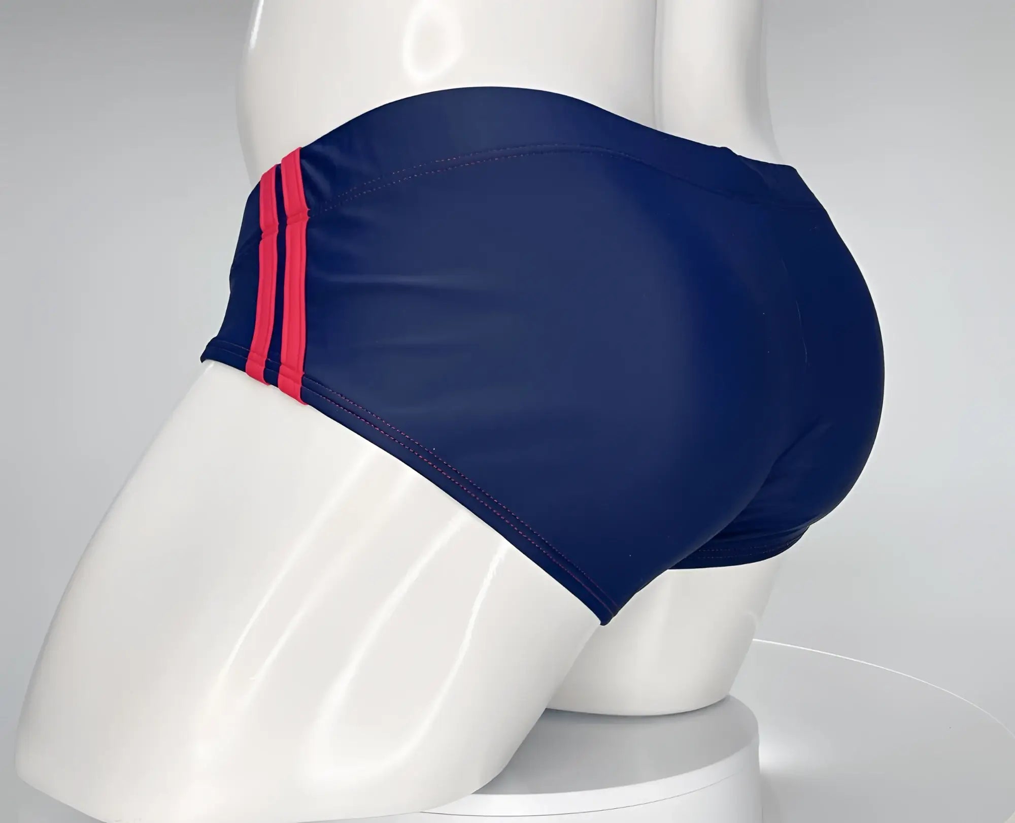 WildmanT navy blue swim brief with two vertical red stripes on the side, displayed on a white mannequin.