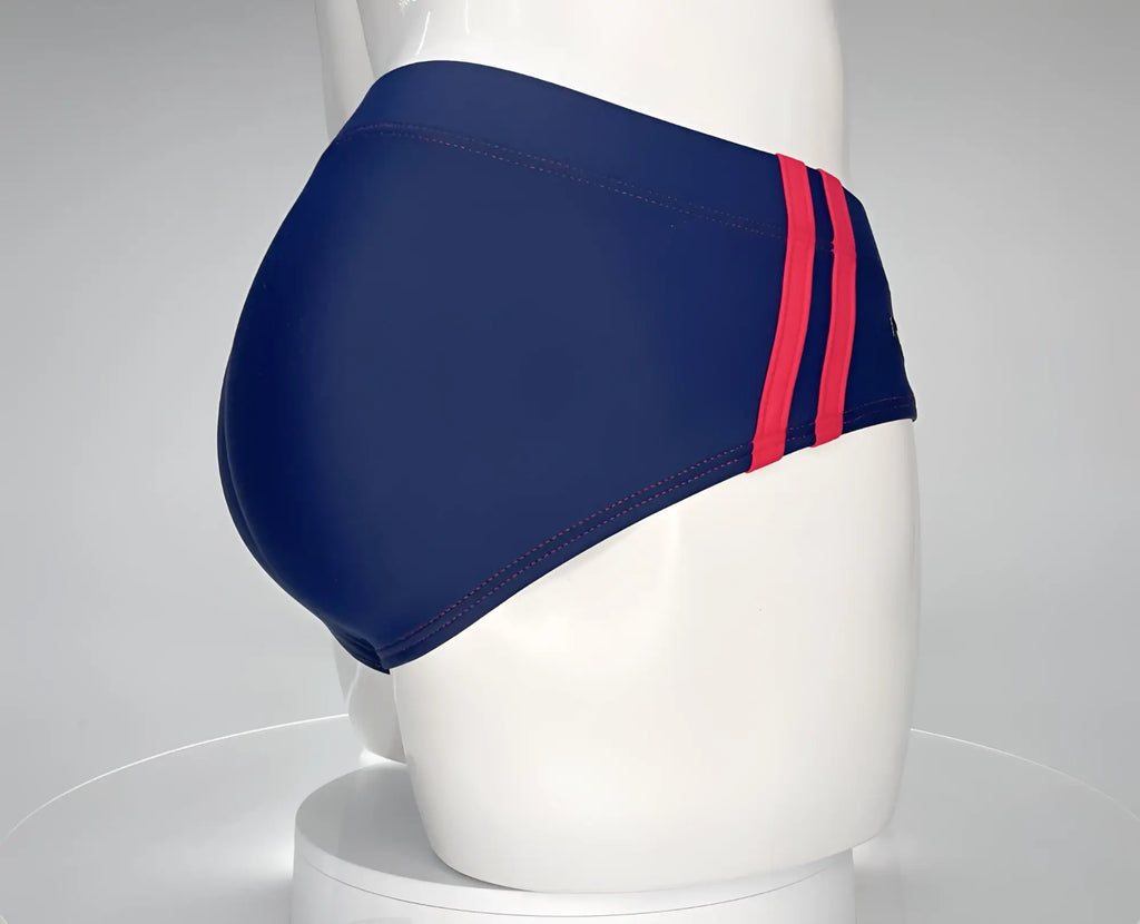 Navy blue swim brief with two red side stripes on a mannequin, viewed from the rear.
