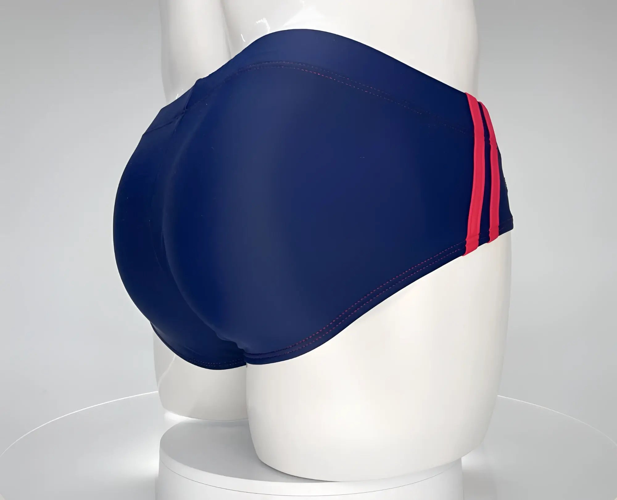Navy blue WildmanT swim brief with red side stripes and red contrast stitching, shown on a white mannequin.